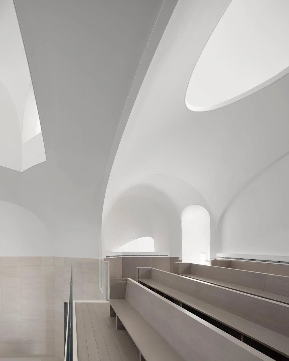 Modern interior with white curved walls and windows, minimalistic design.