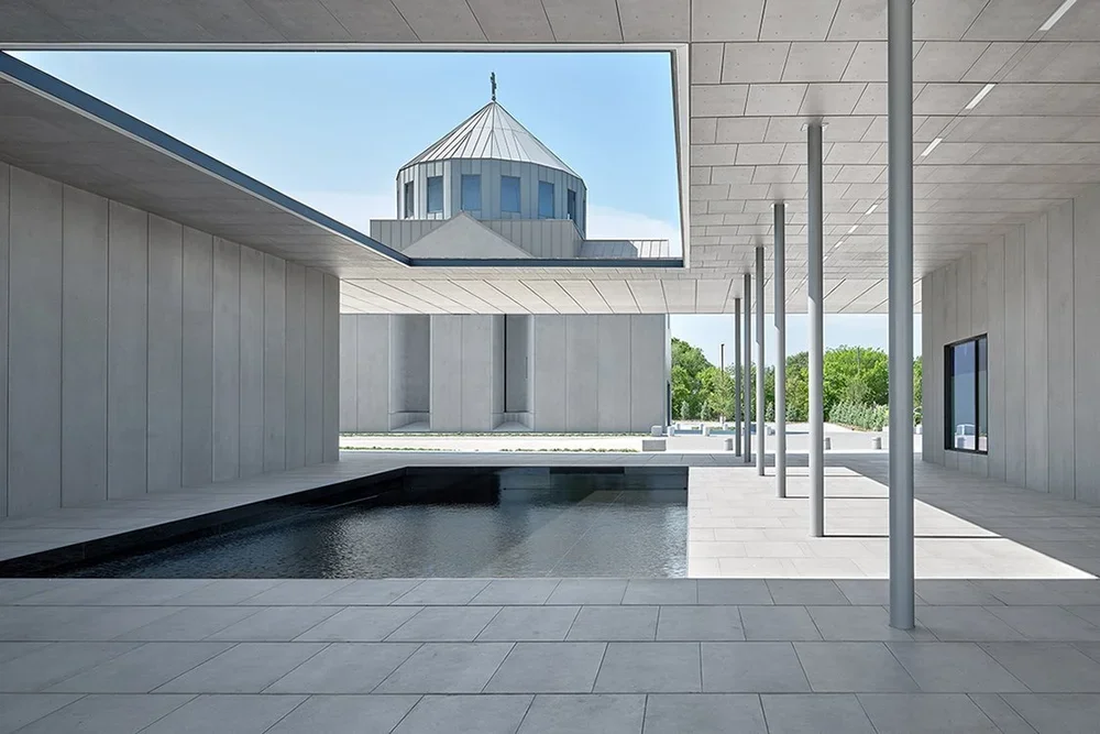 Modern architectural design with a rectangular swimming pool, columns, and an opening in the ceiling showing a domed building outside