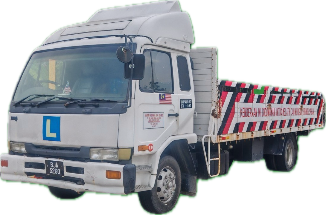 White flatbed truck with a blue 'L' sign on the front, a Malaysian flag sticker on the door, and a sign with safety instructions. The flatbed has a red and white striped pattern with green accents and safety warnings.