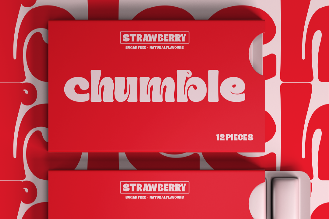 Red boxes of Strawberry Chumble candy with white and gray text, placed on a red and white patterned background.