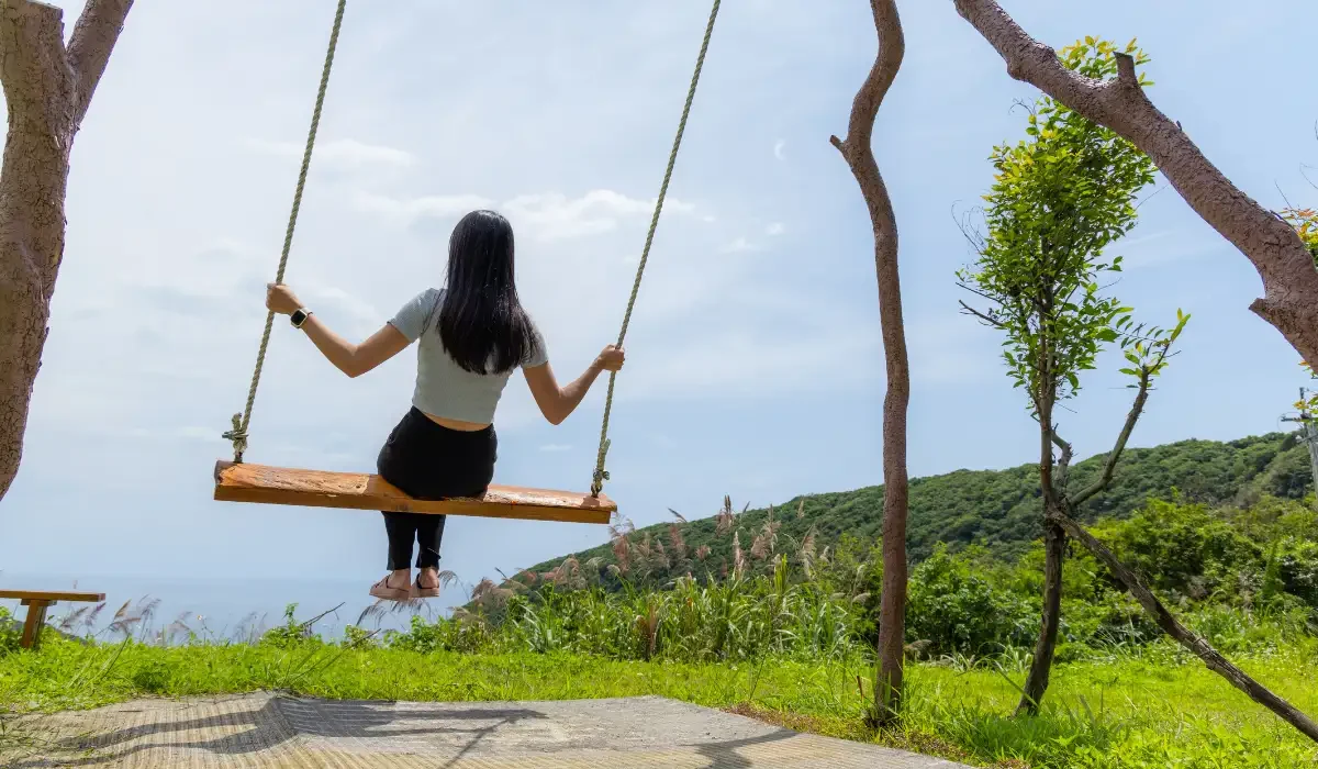 An woman on a swing surrounded by nature.