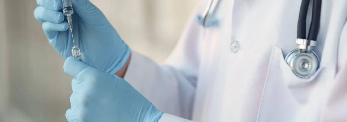 Medical professional in blue gloves preparing a syringe with a vaccine or medication.