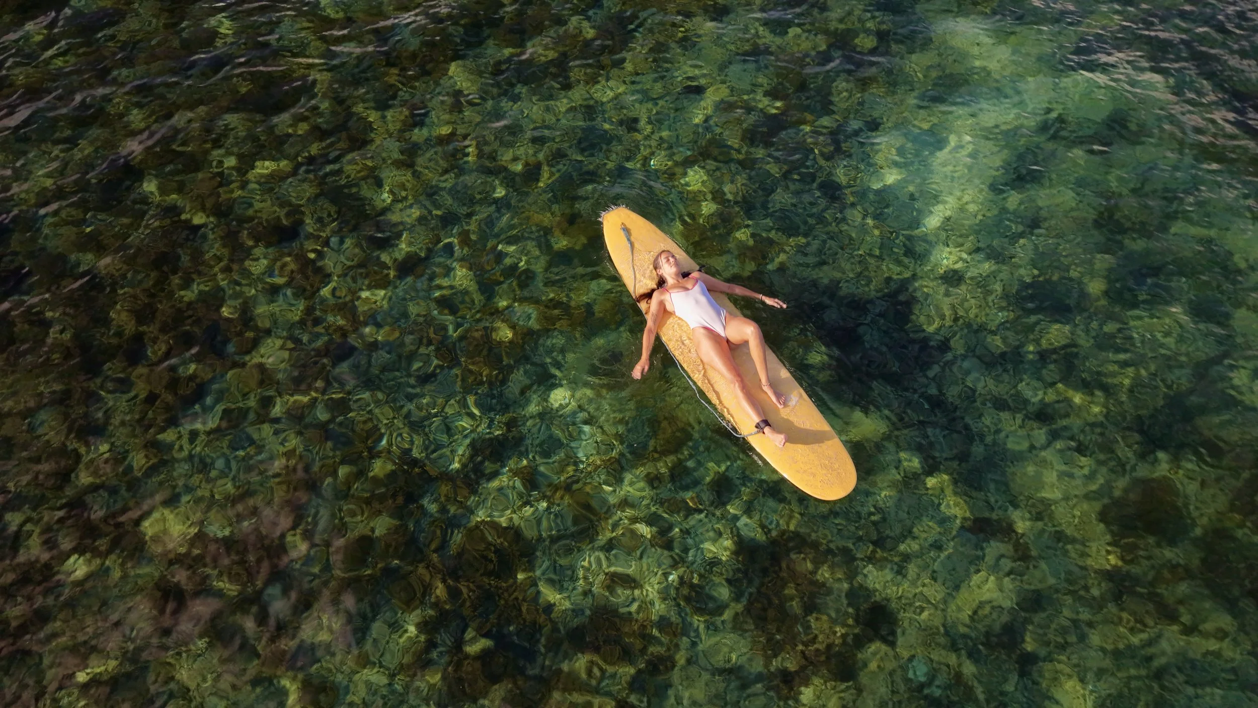 a guest lying on their surfboard at their swimfit retreat