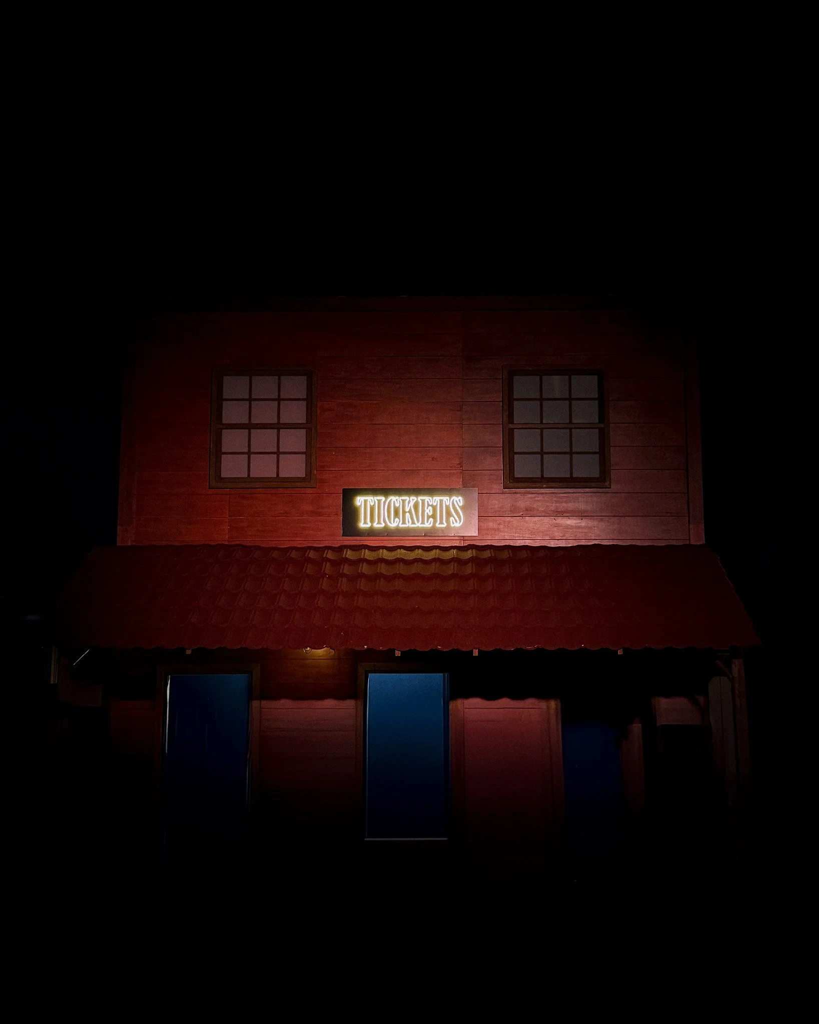 Nighttime view of a red building with a neon sign that reads 'TICKETS' above the entrance