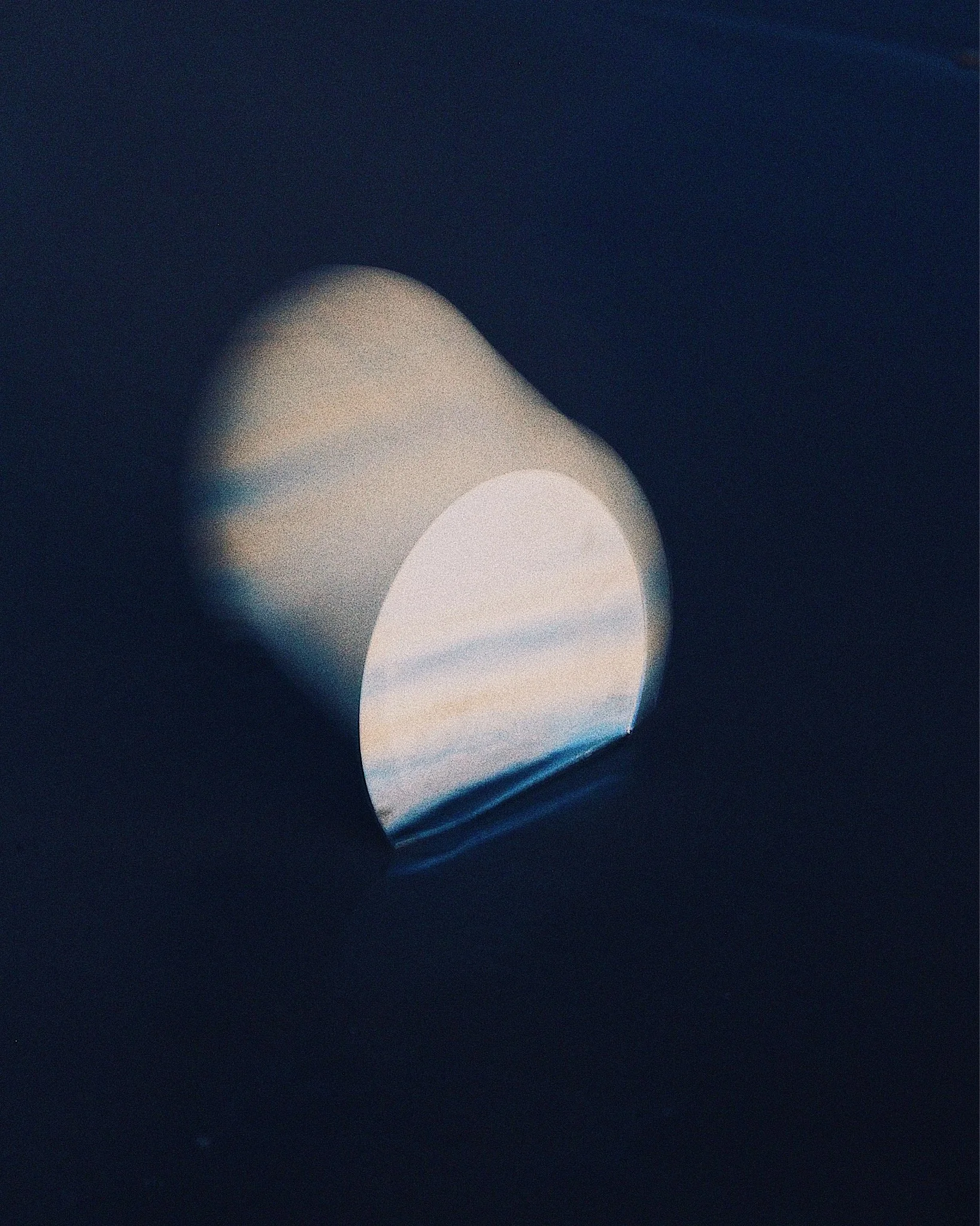 A photograph of a porthole window on a ship looking out to the ocean with blue sky and clouds.