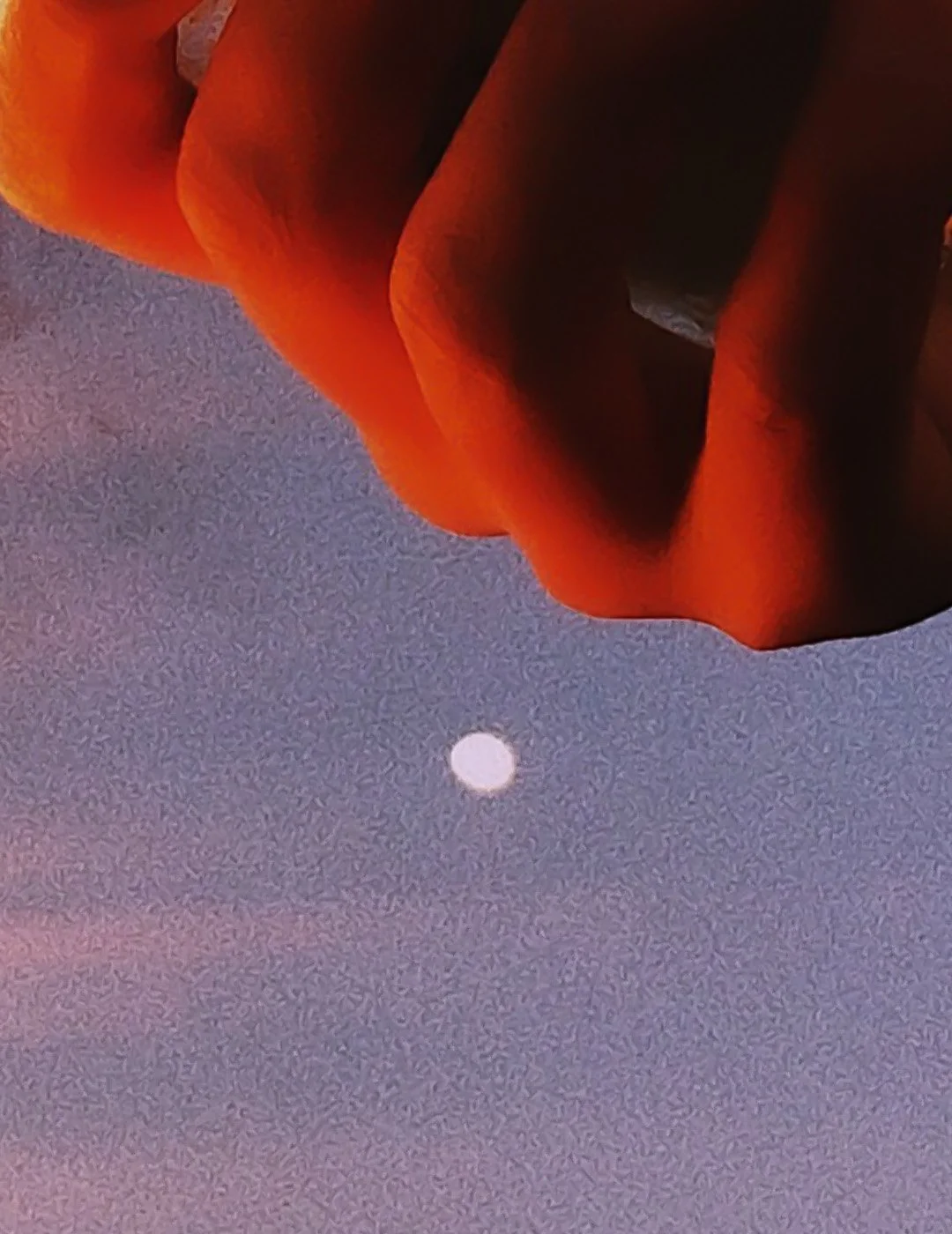 Close-up of a person's face wearing an orange hooded jacket, with the night sky and a visible full moon in the background.