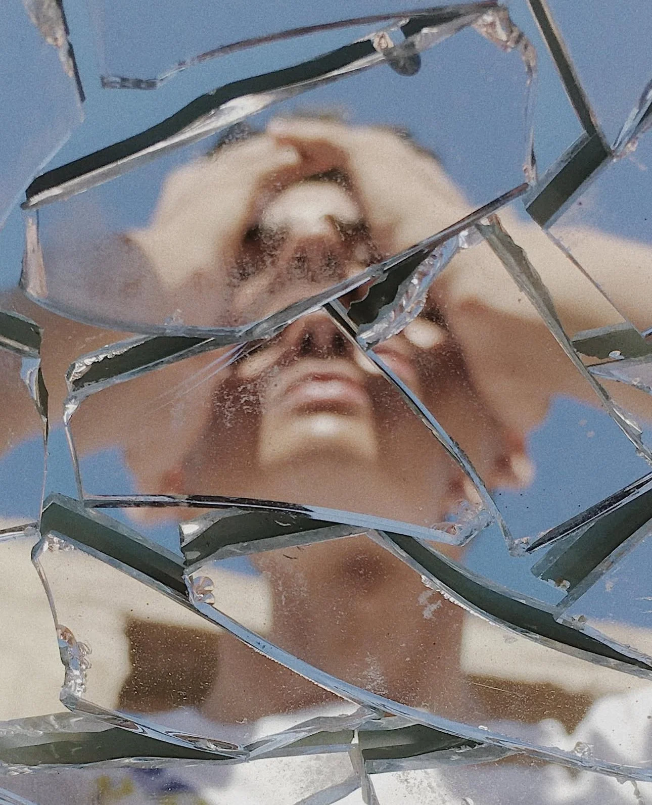 A person looking through shattered glass with a blue background.
