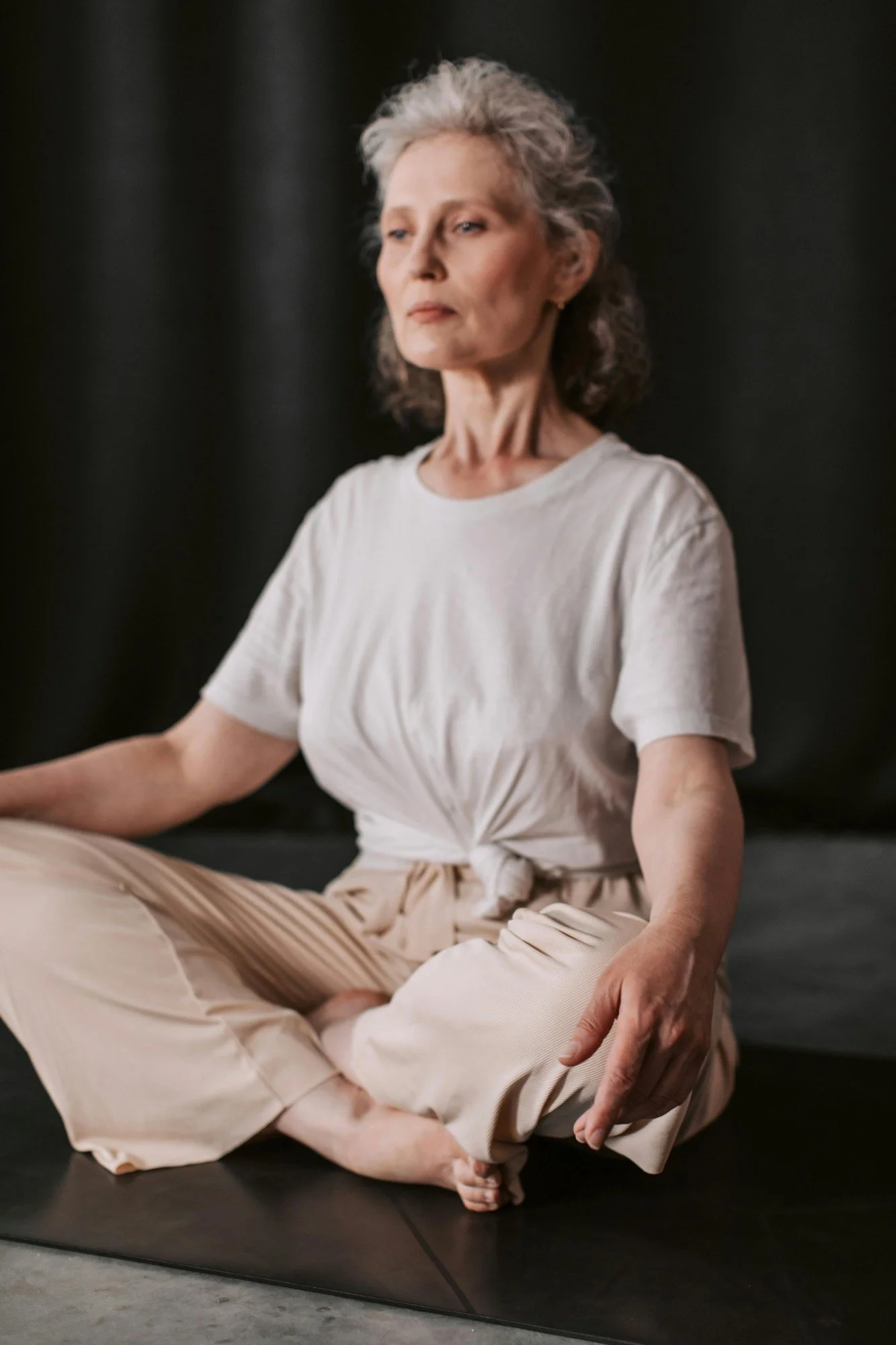 Woman sat cross-legged on a yoga mat with her eyes closed