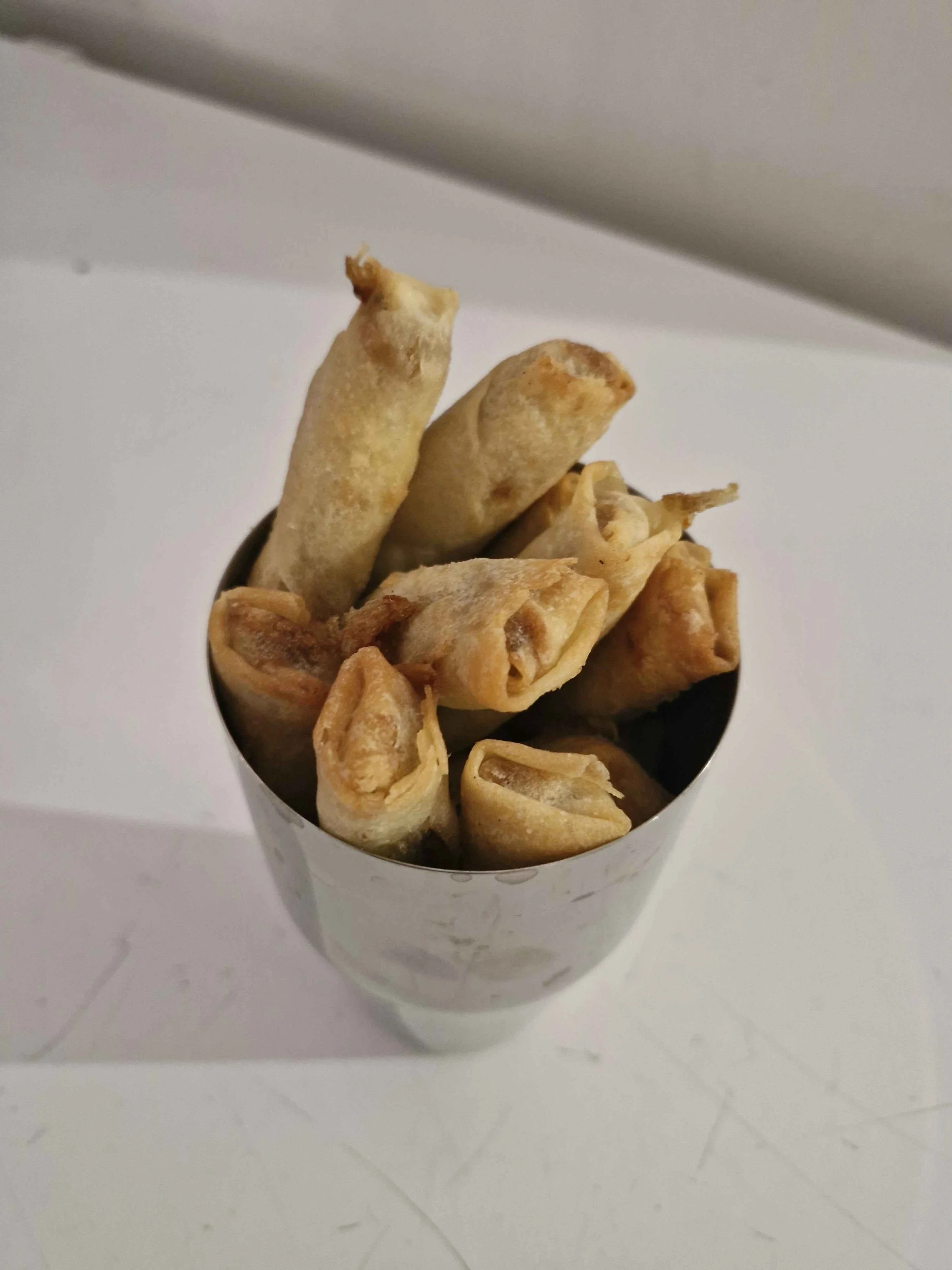 SPORKS IDEA OF KEEPING SPRING ROLLS WARM WHILE PLAYING.ITS IN A METAL MIXER CUP.