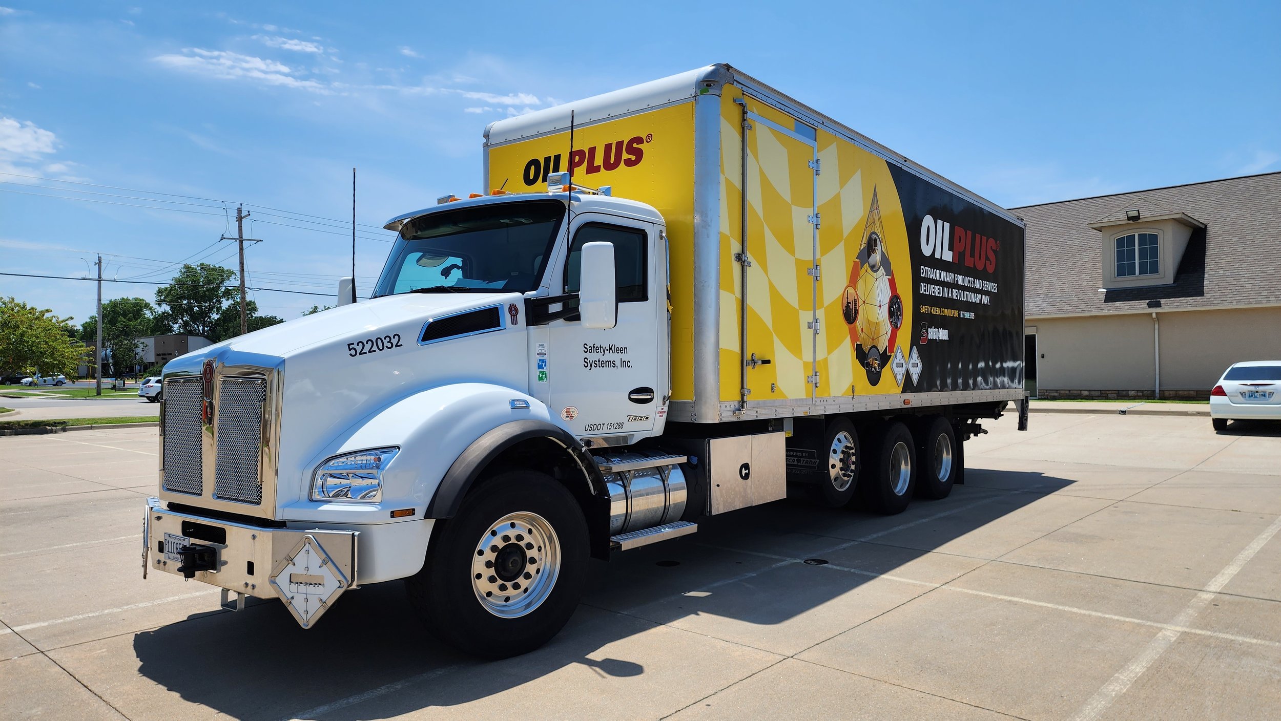 White semi-truck with yellow and black trailer branded 'OILPLUS' parked in a lot.