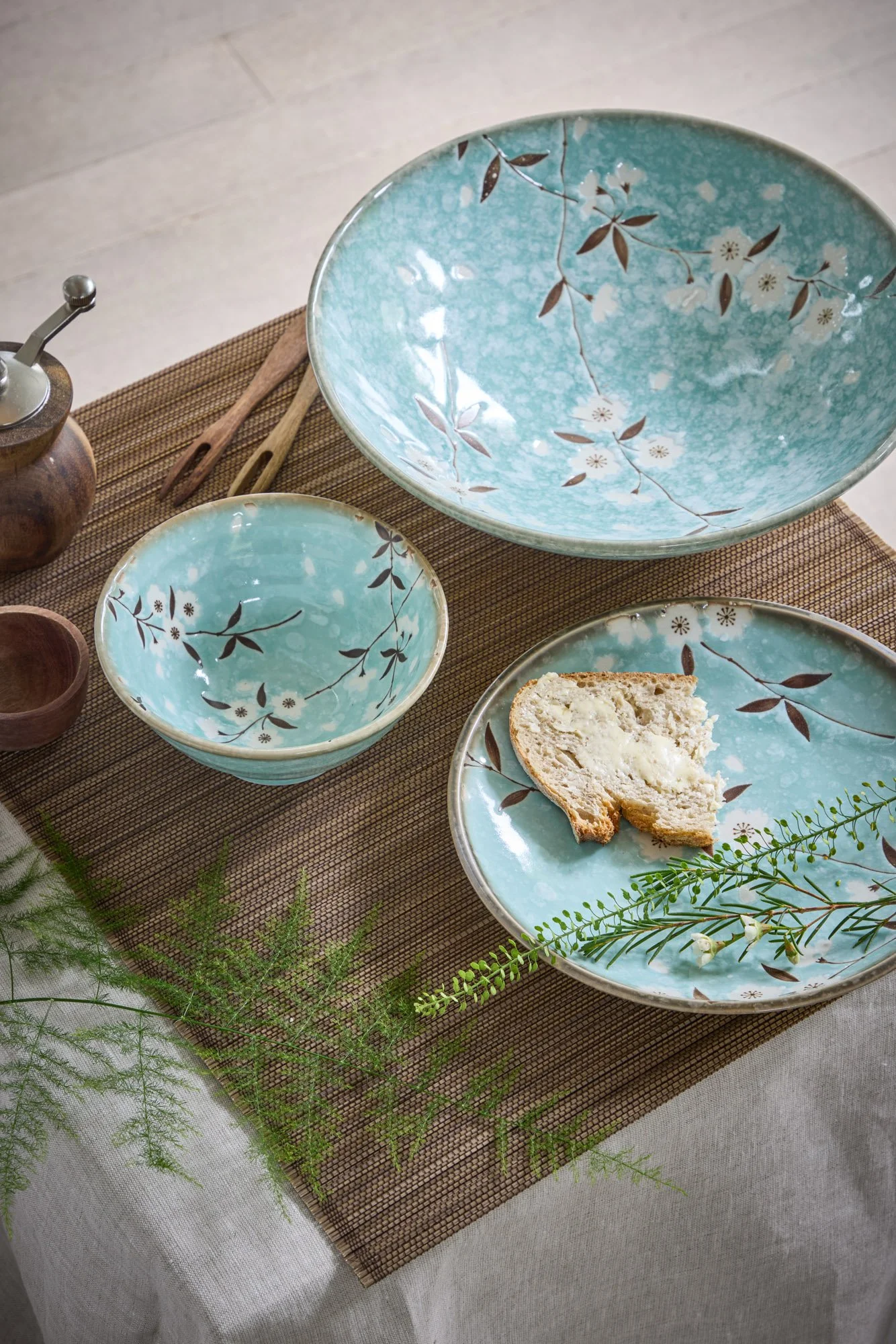 Tokyo Design Studio turquoise floral Japanese tableware - large serving bowl, small bowl and plate with white blossom design, styled with wooden salad servers and bread