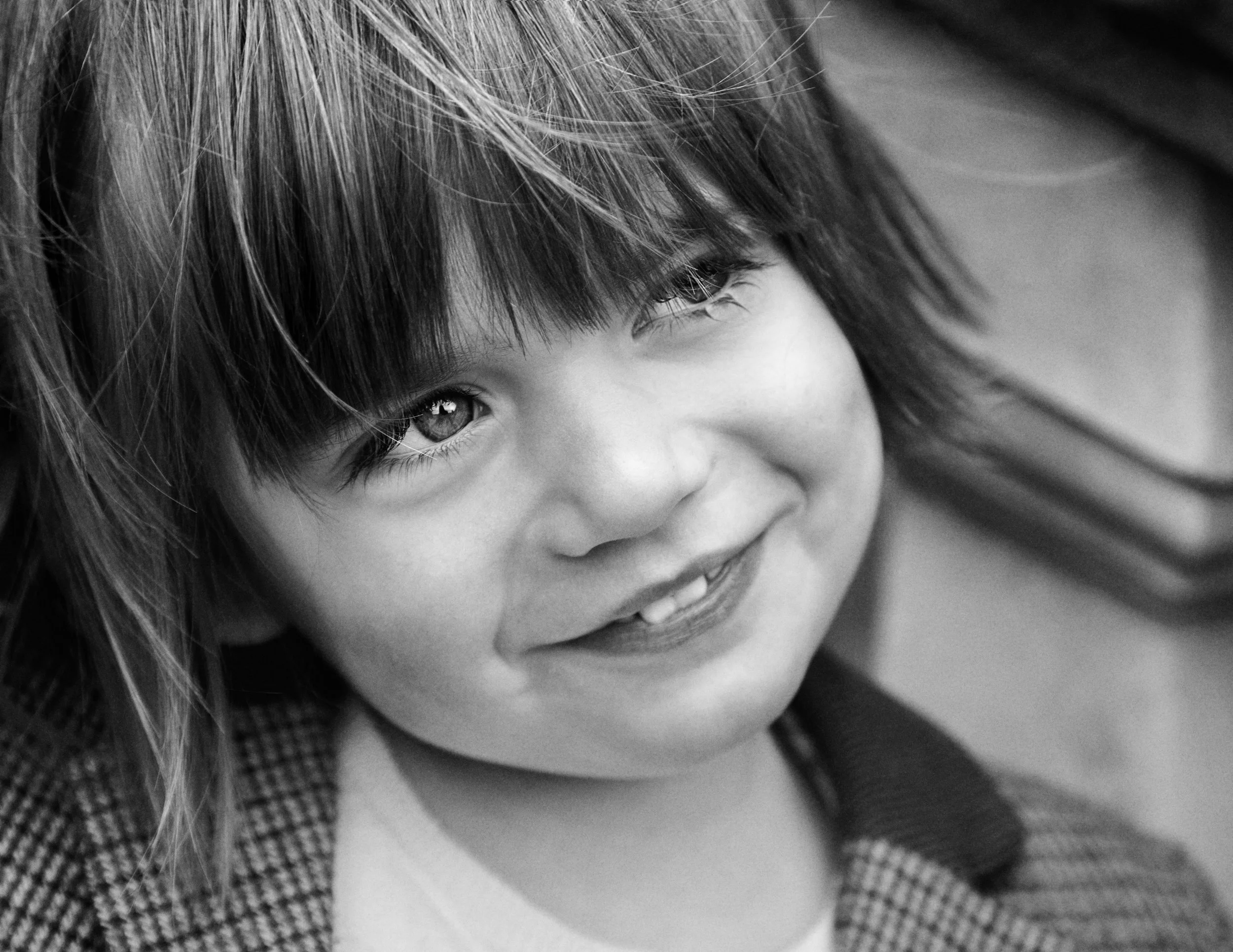 Black and white image of a young boy with long hair smiling and looking away from the camera