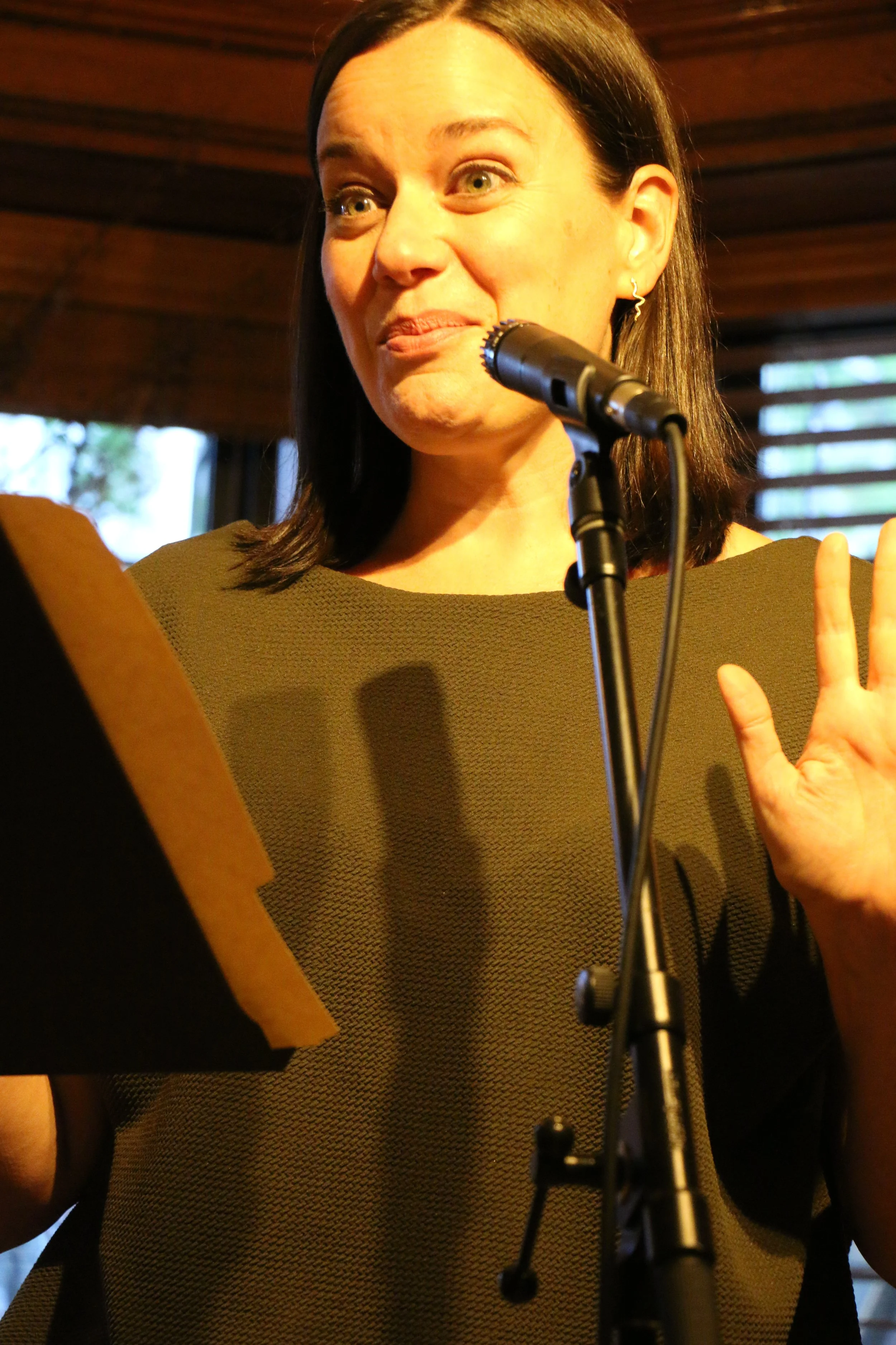 Woman speaking at a microphone with expressive gestures