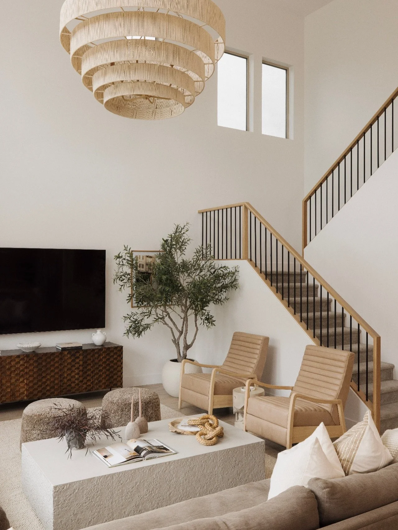 Details from our #MaisonViolaByGHD living room. 

Warm wood tones, worn-in leather, and a concrete coffee table that keeps the space textured and grounded. Layered browns bring depth without heaviness, while a rattan chandelier overhead adds texture 