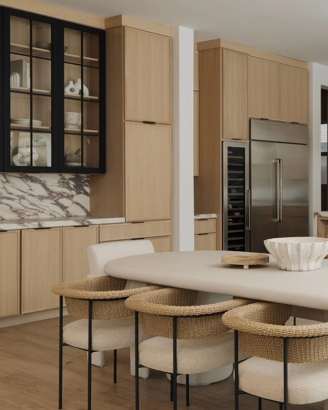 Grounded textures and sculptural lines define the dining area in #MaisonViolaByGHD. A soft, curved table paired with woven statement seating brings warmth and balance to the bold stone moments throughout the space, while natural wood tones and brass 