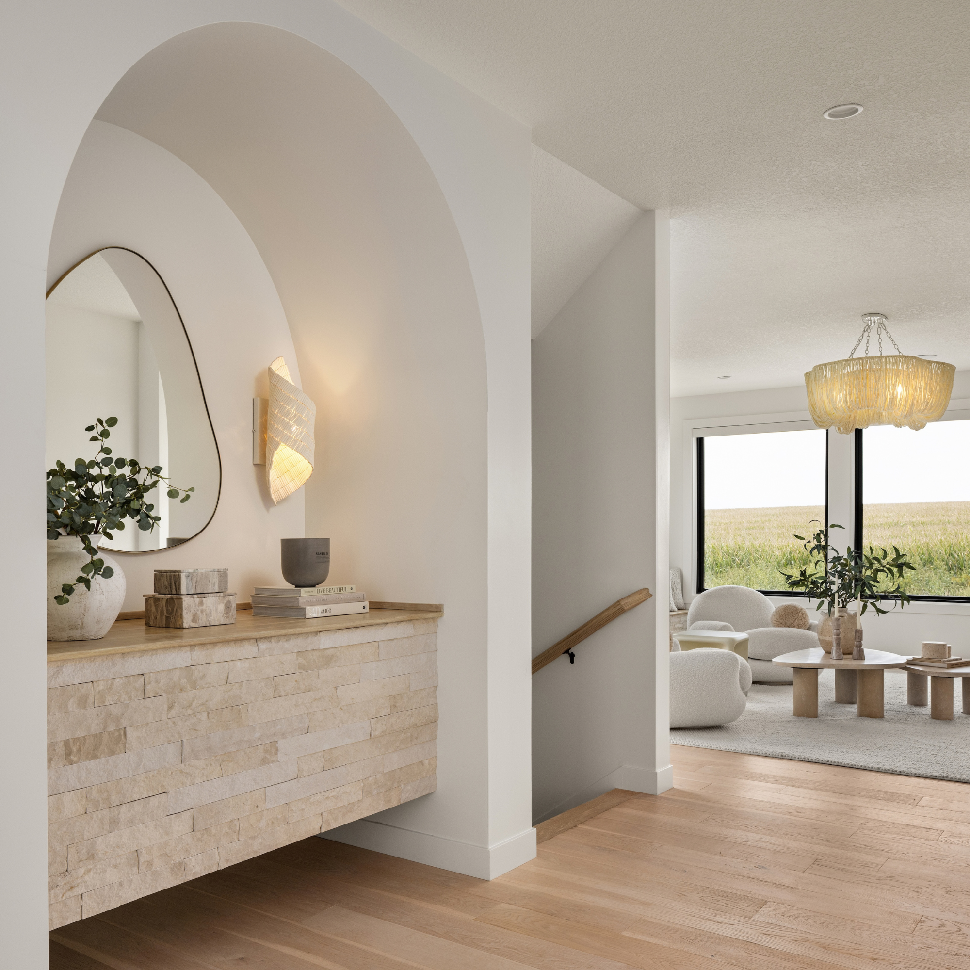 Neutral entryway featuring curved arch walls and sconces from luxury interior design project.