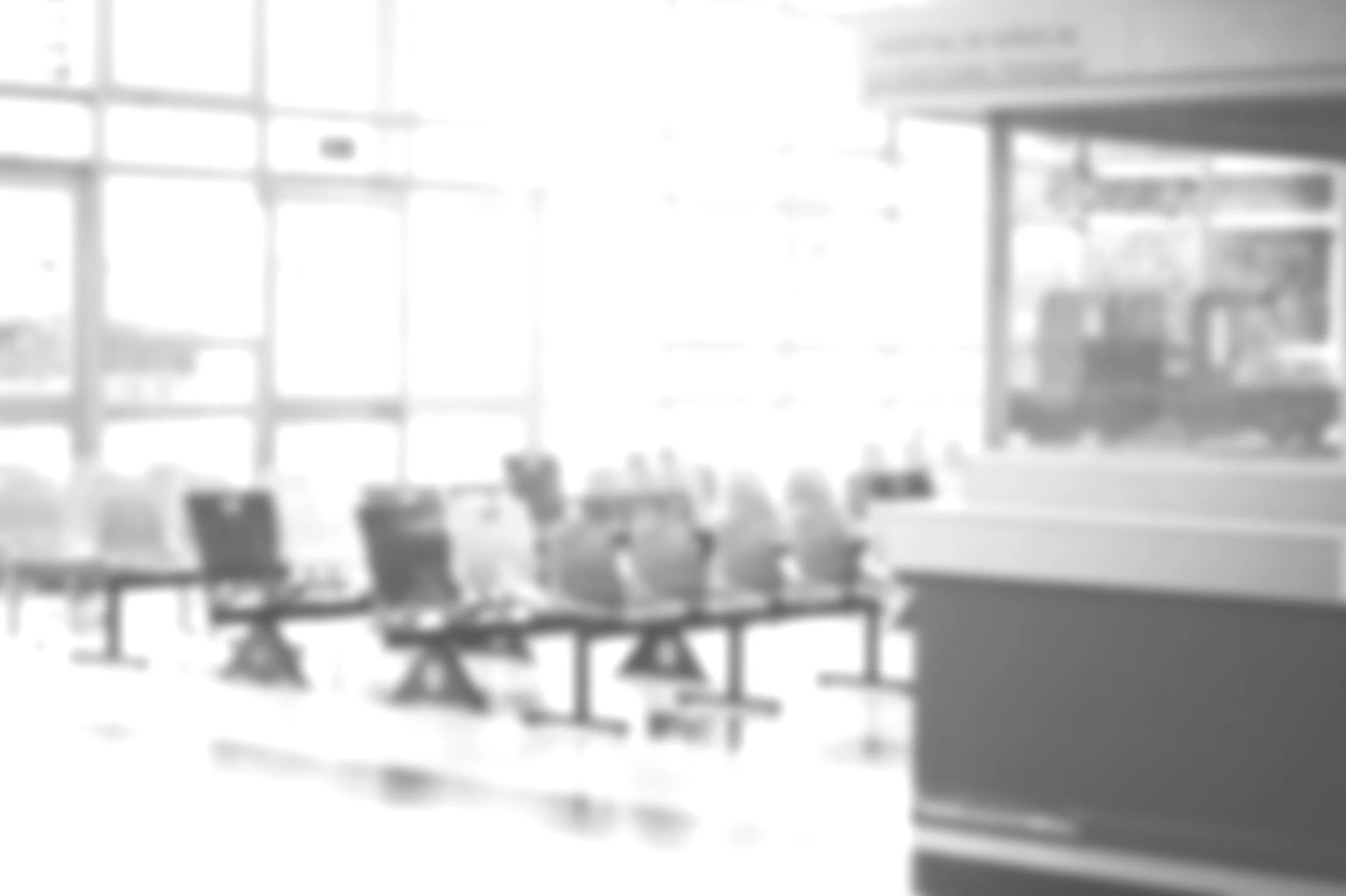 Blurred image of empty airport seating area with large windows and information desk