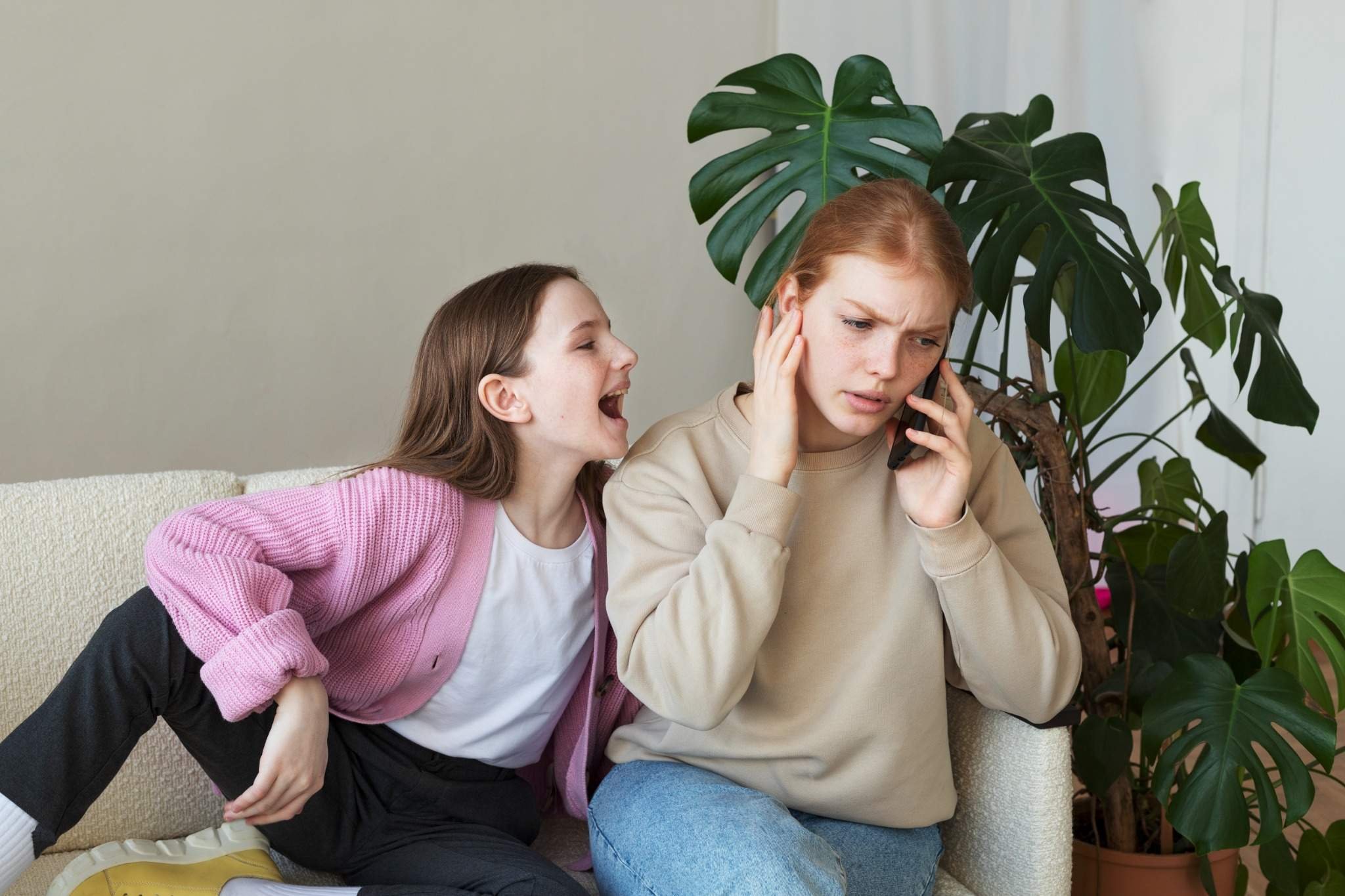 Kind nervt ihre große Schwester, die am Telefon ist, Geschwisterstreit, Familienberatung hilft