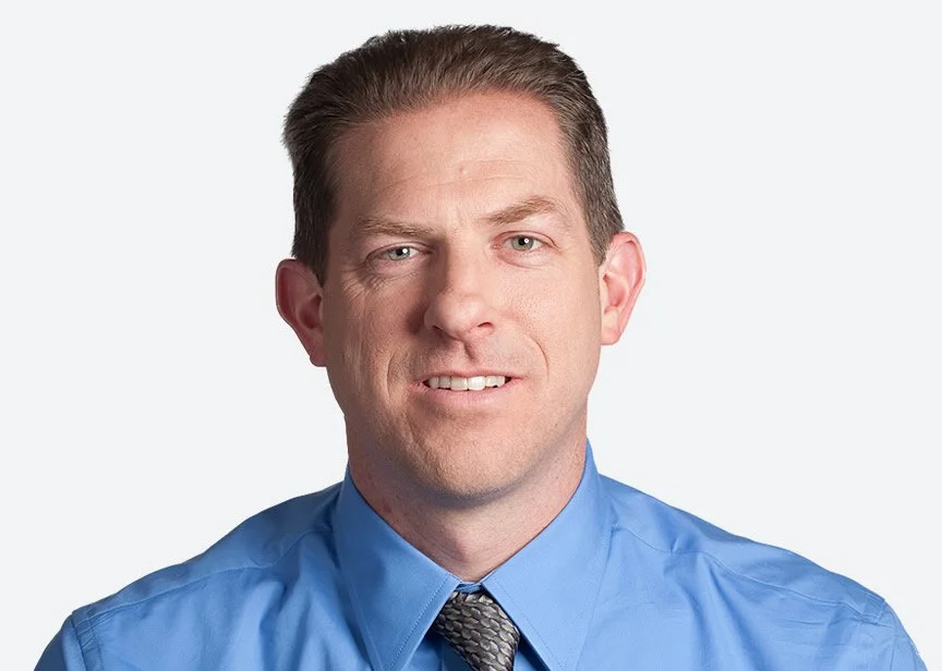 A man in a blue shirt and tie on a white background