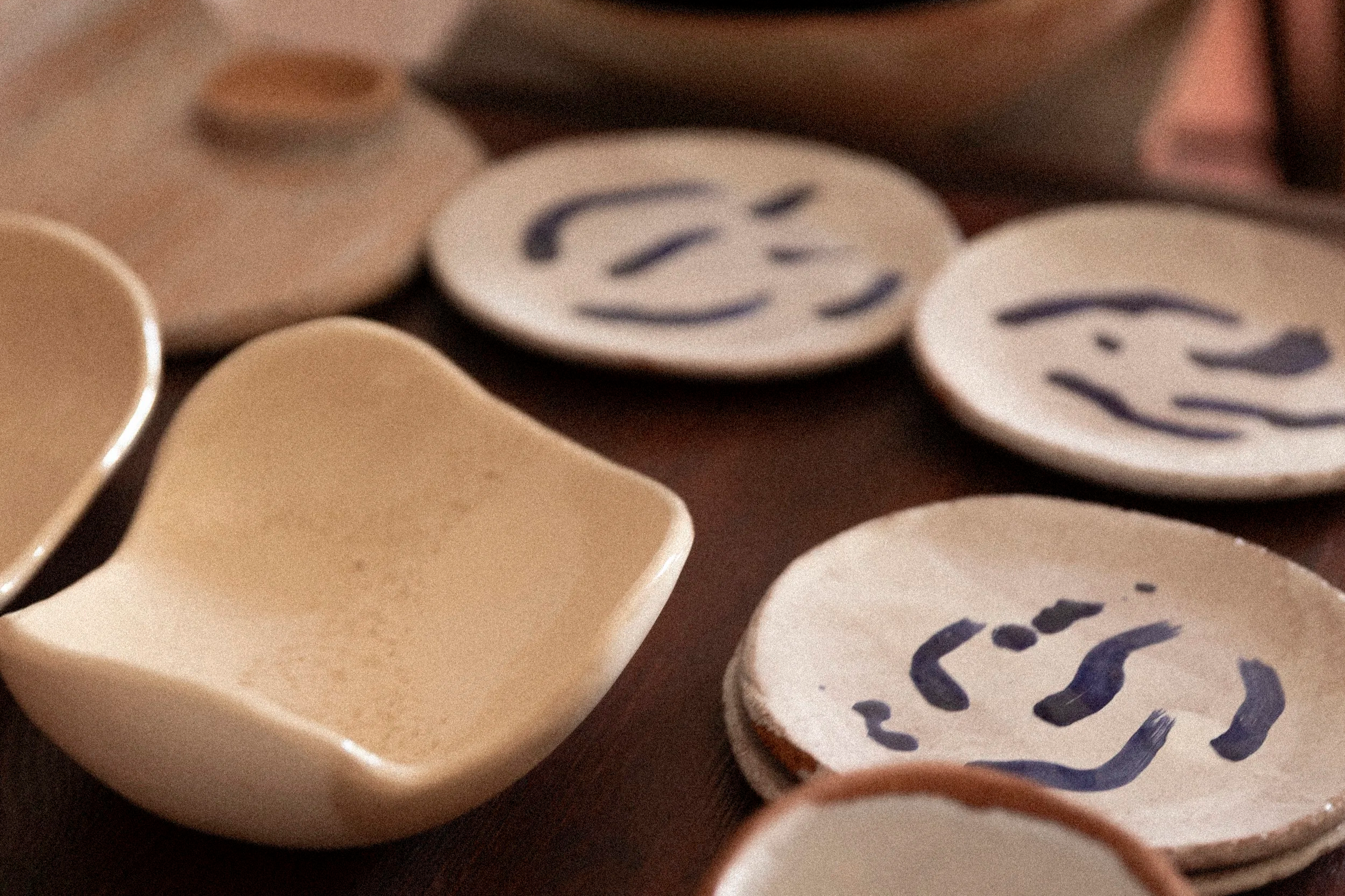 Mehrere runde Keramikuntersetzer, einige mit Smileys und Zeichnungen.