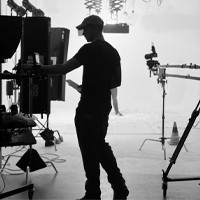 Behind-the-scenes photo of a person operating camera equipment on a film set.