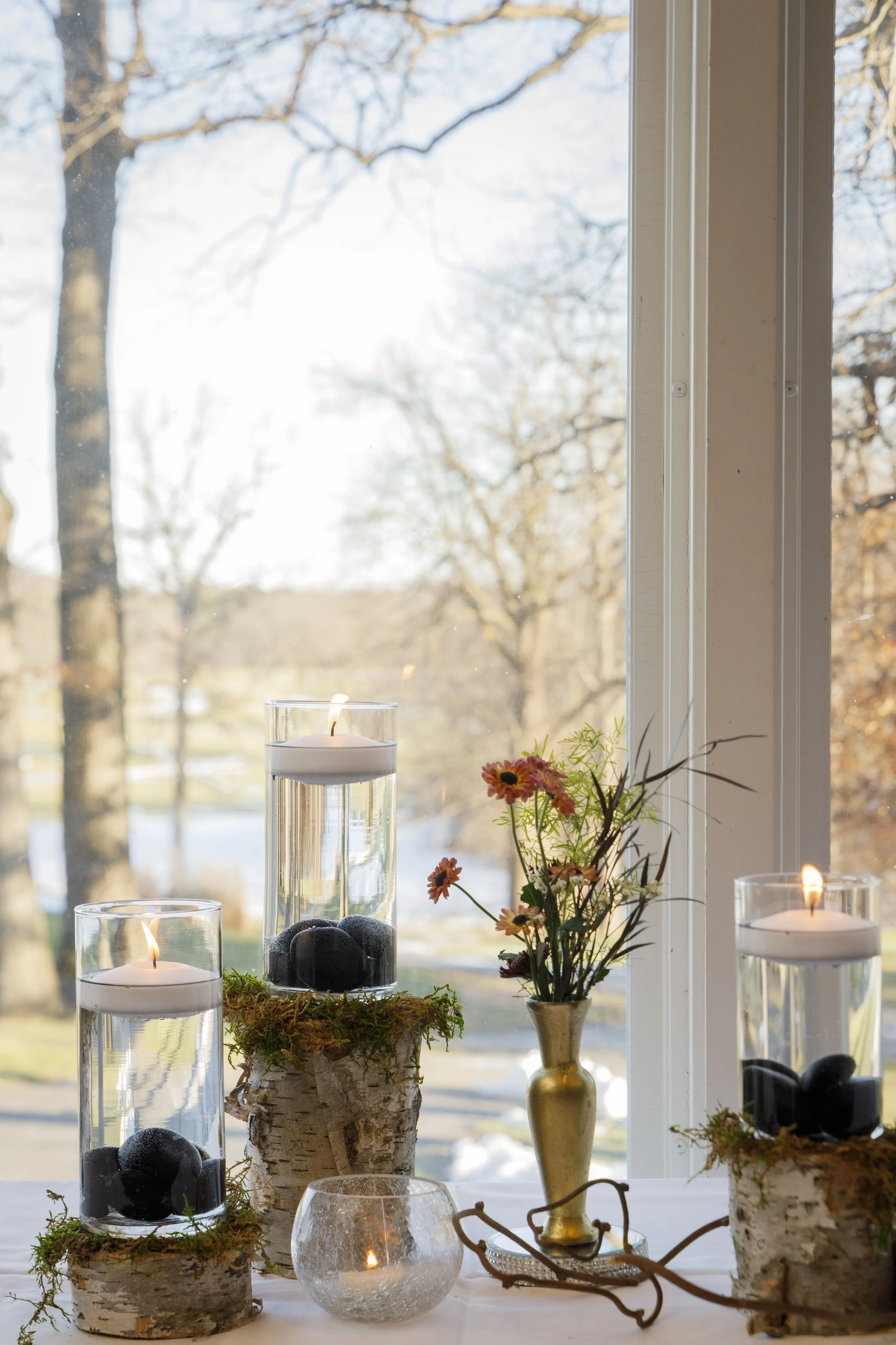 Scenic landscape with a large turquoise lake, rolling grassy hills, and rugged mountains in the background under a cloudy sky.