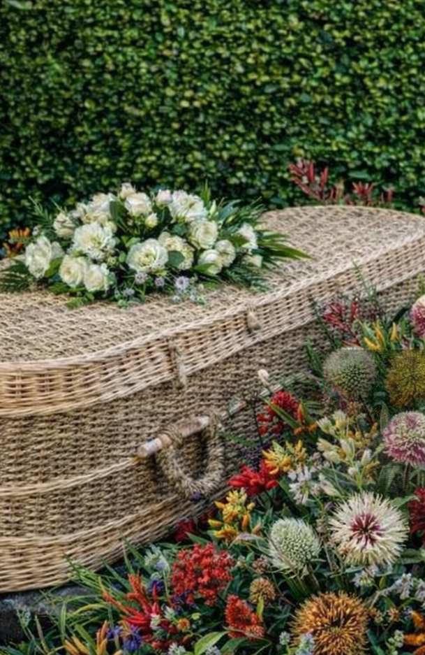 A wicker coffin placed in a serene garden setting, surrounded by greenery and flowers.