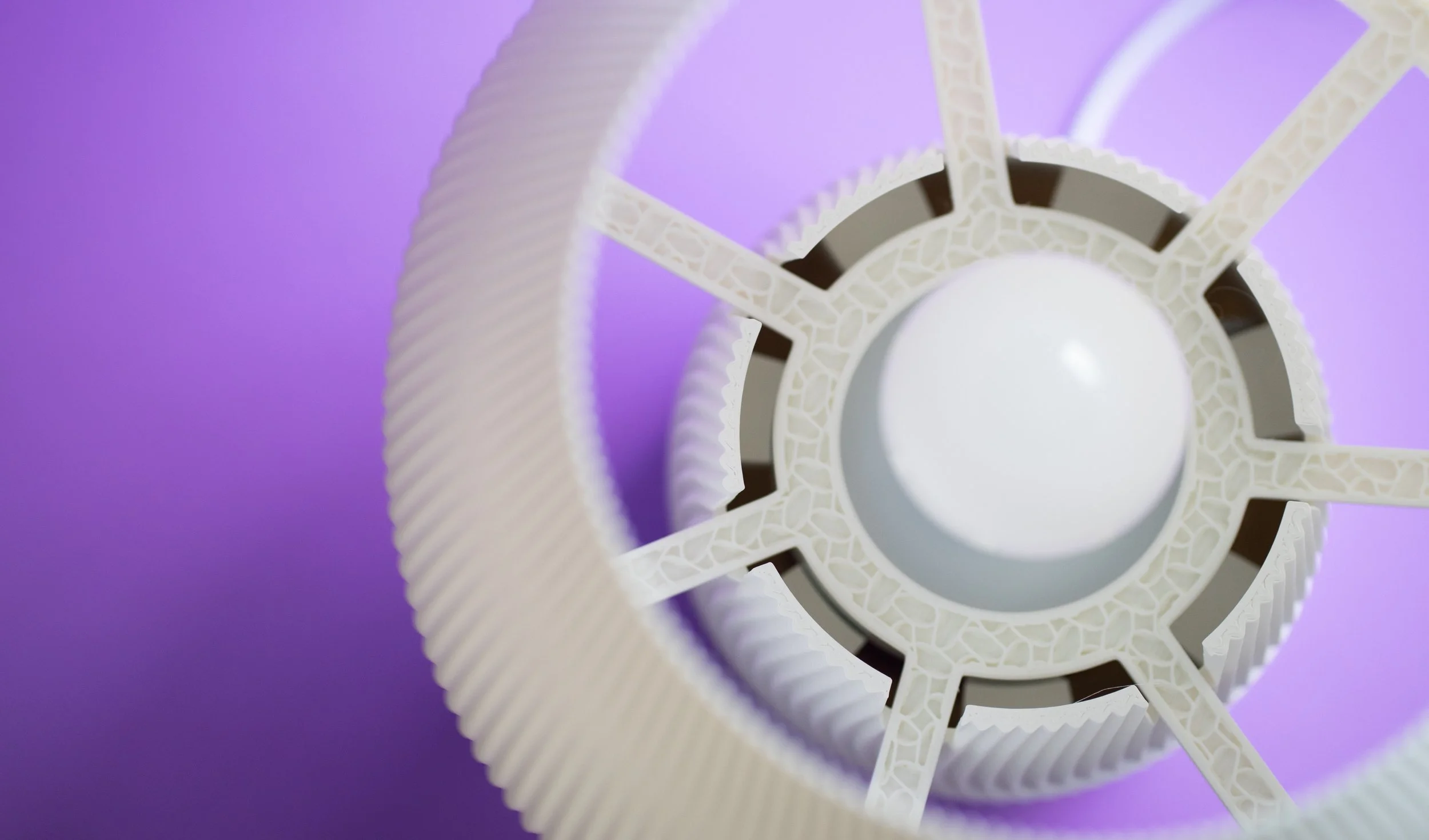 Close-up of a gear-like structure with a circular white center on a purple background.