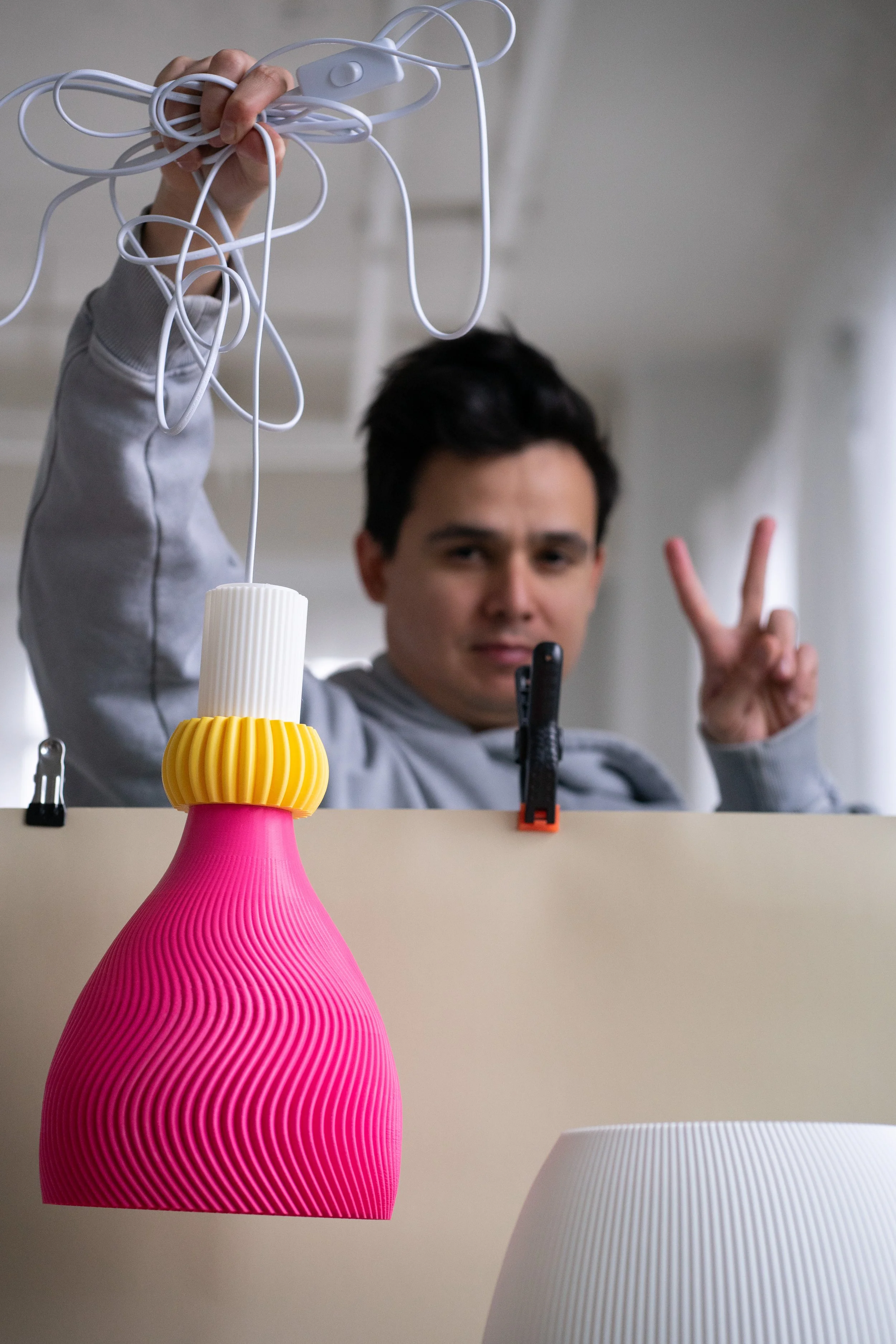 Person holding pink and yellow lamp with peace sign.