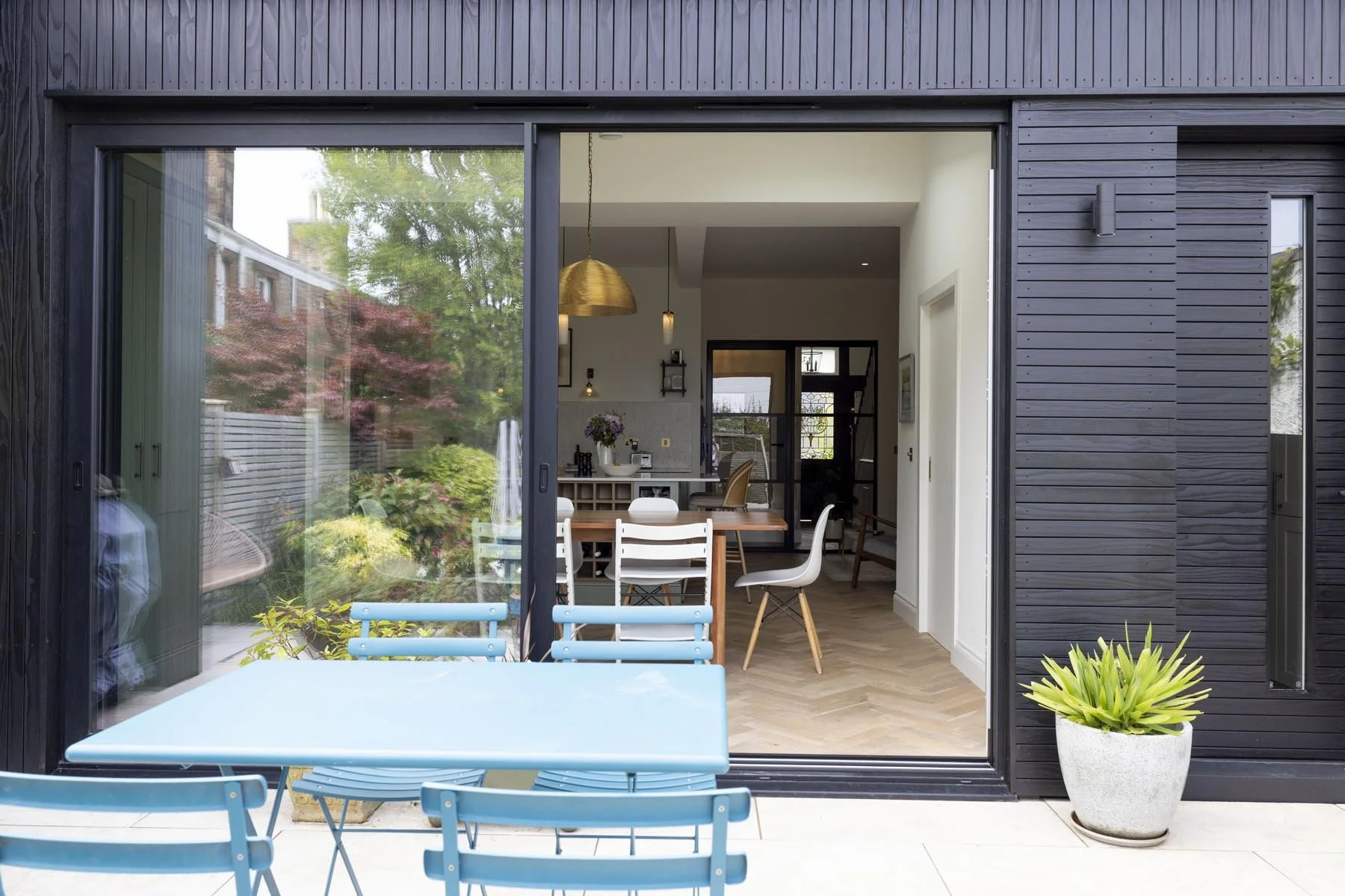 black aluminium sliding doors to rear extension in morningside edinburgh with patio and blue table designed by edinburgh architect