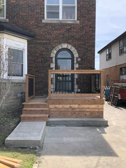 Front view of a brick house with a wooden porch and steps