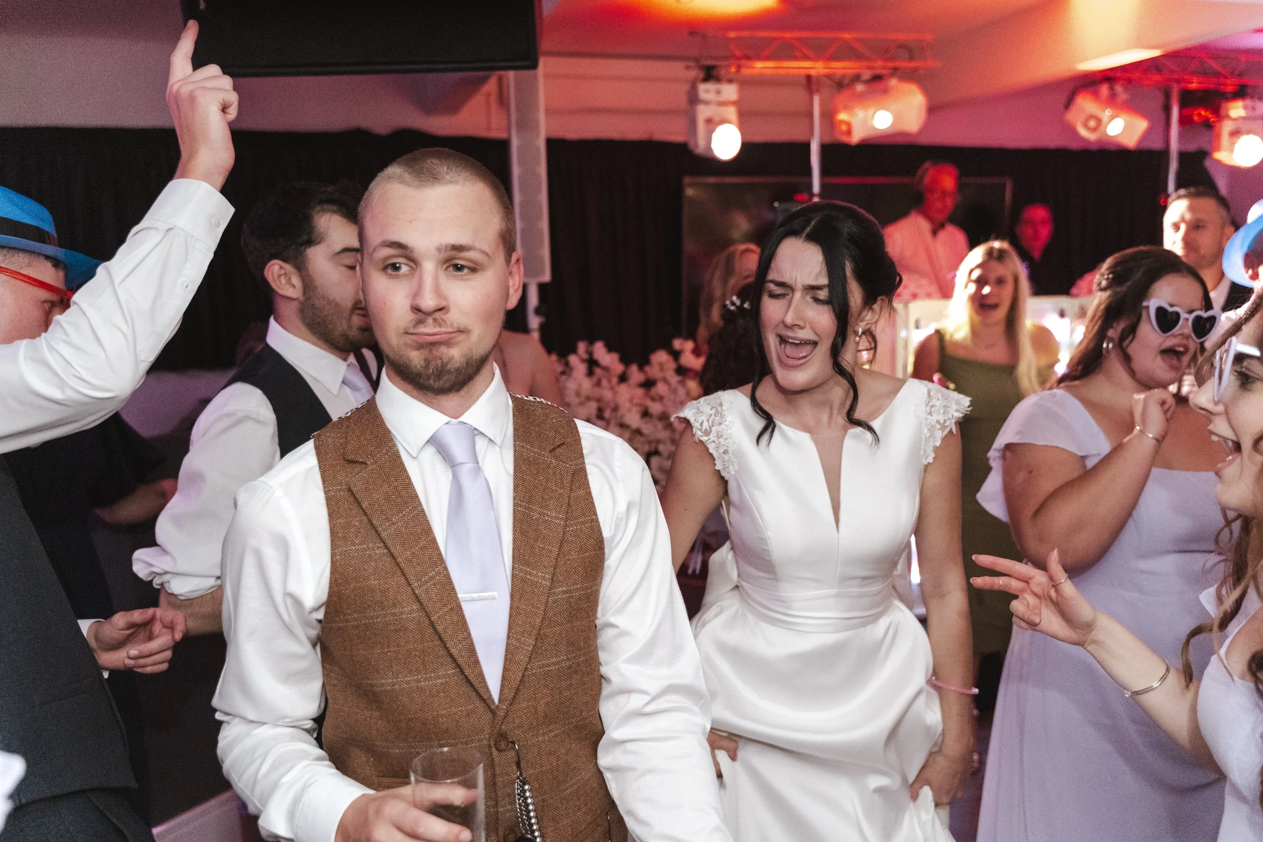 People dancing and socializing at a party with colorful lighting and decorations.
