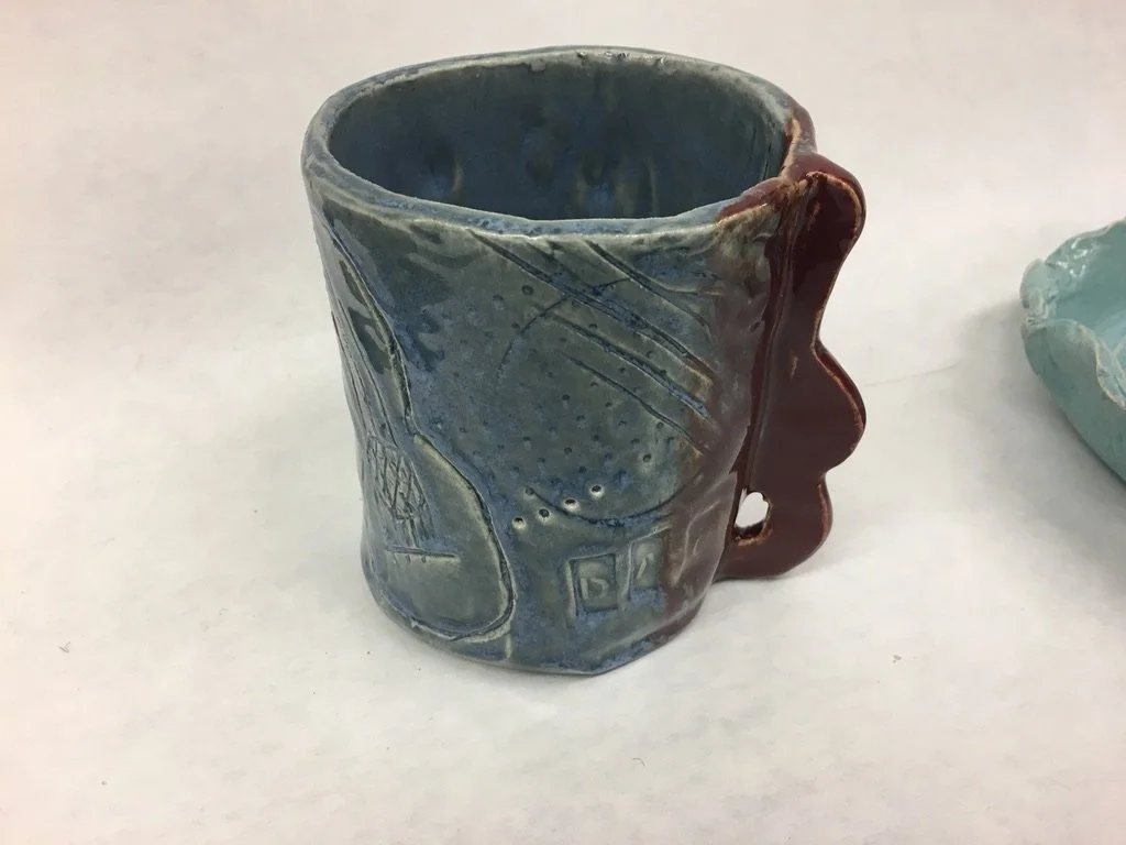 Handcrafted ceramic mug with blue glaze and abstract designs