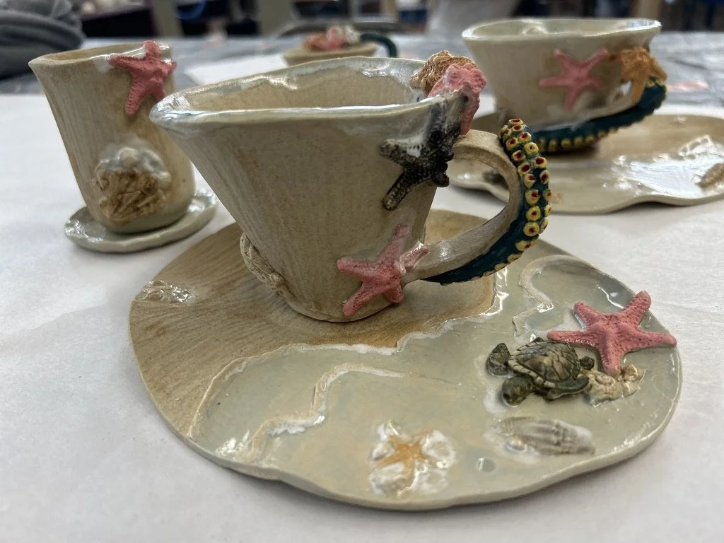 Ceramic teacup and saucer set with seashell and starfish decorations.