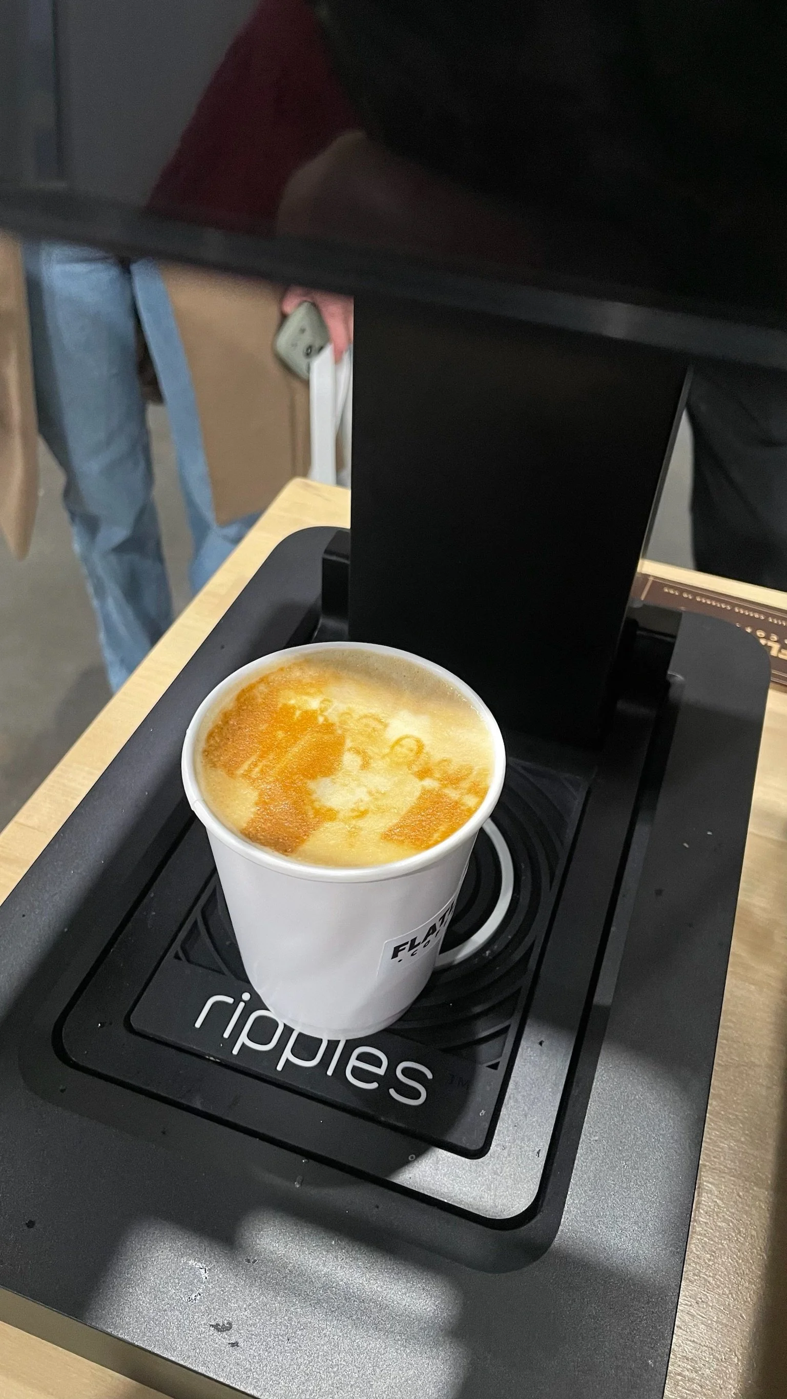 Fresh latte on a latte art printer platform ready to hand to customer