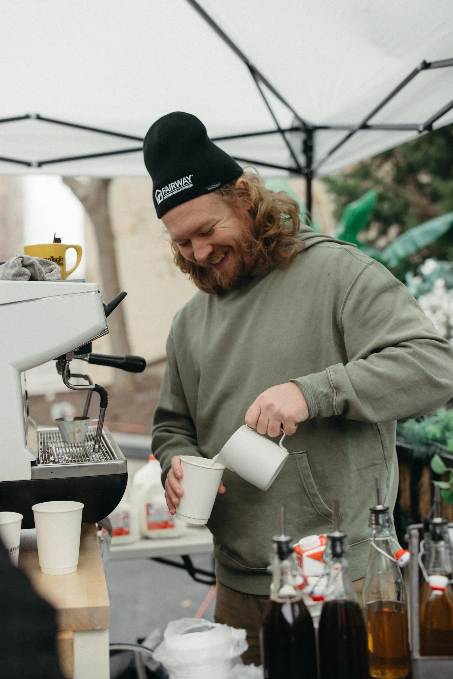 A barista at an event pouring a coffee drink