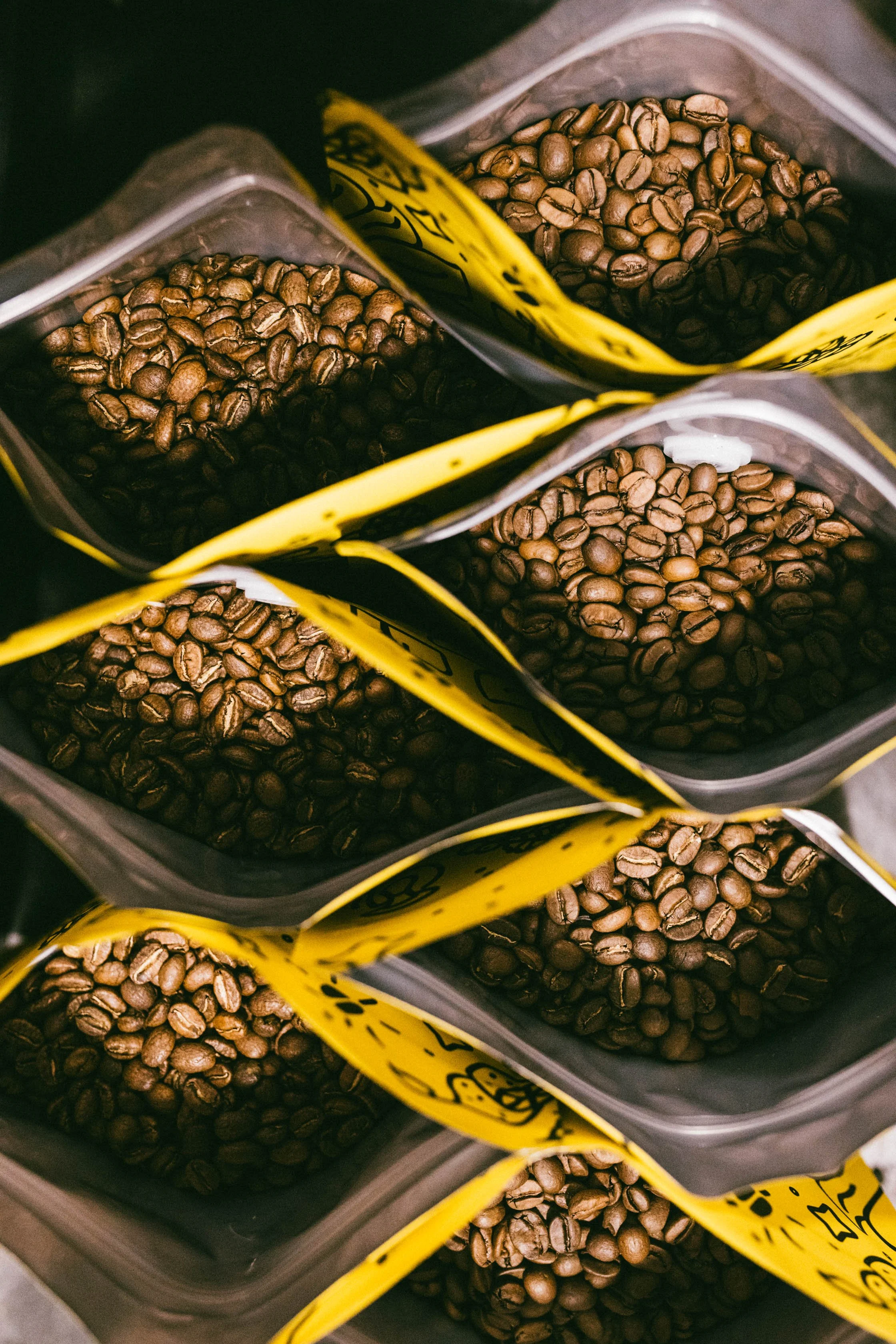 Multiple bags of coffee beans arranged in a grid, with yellow labels.