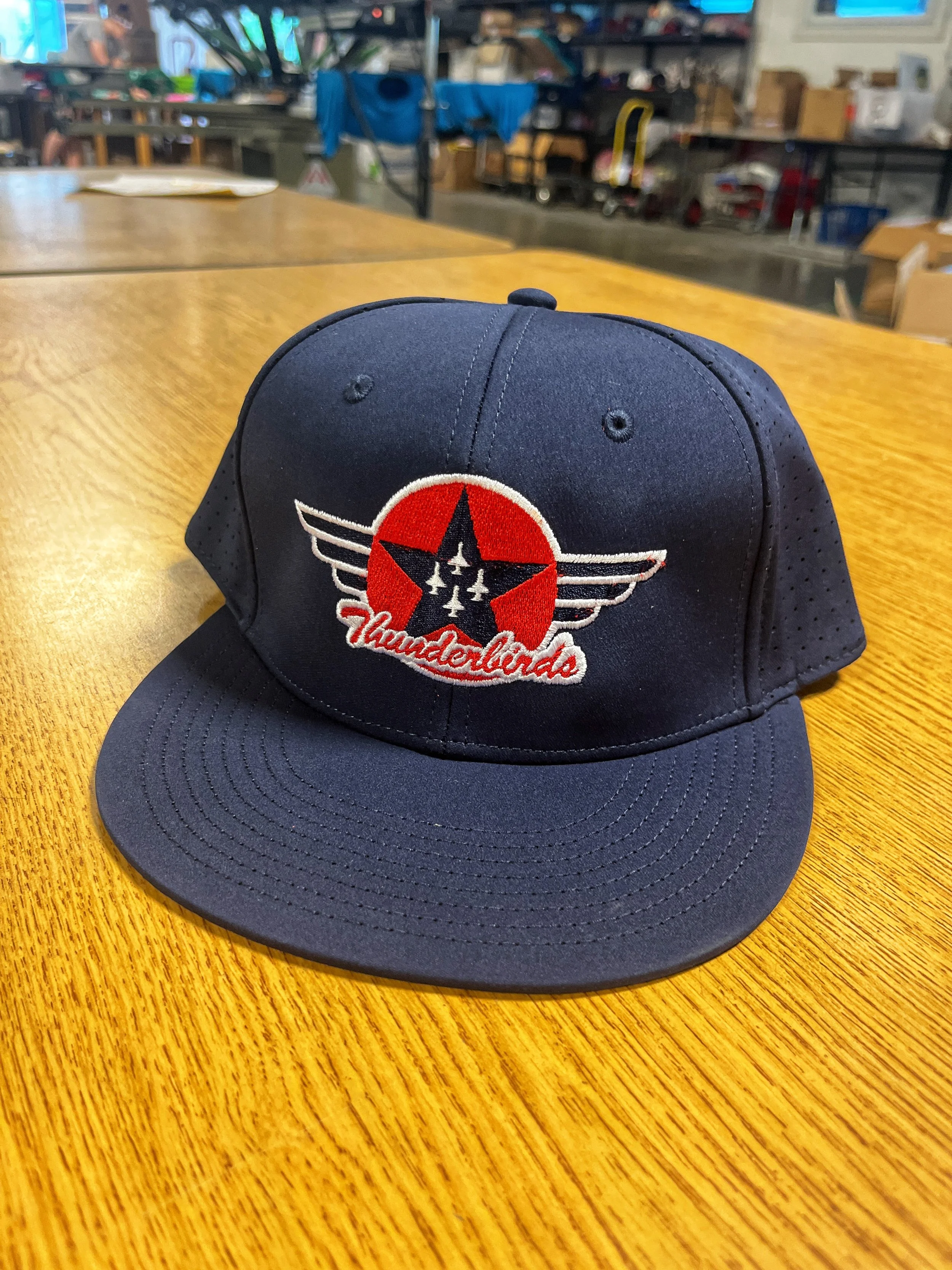 Navy cap with a red, white and black embroidered team graphic.