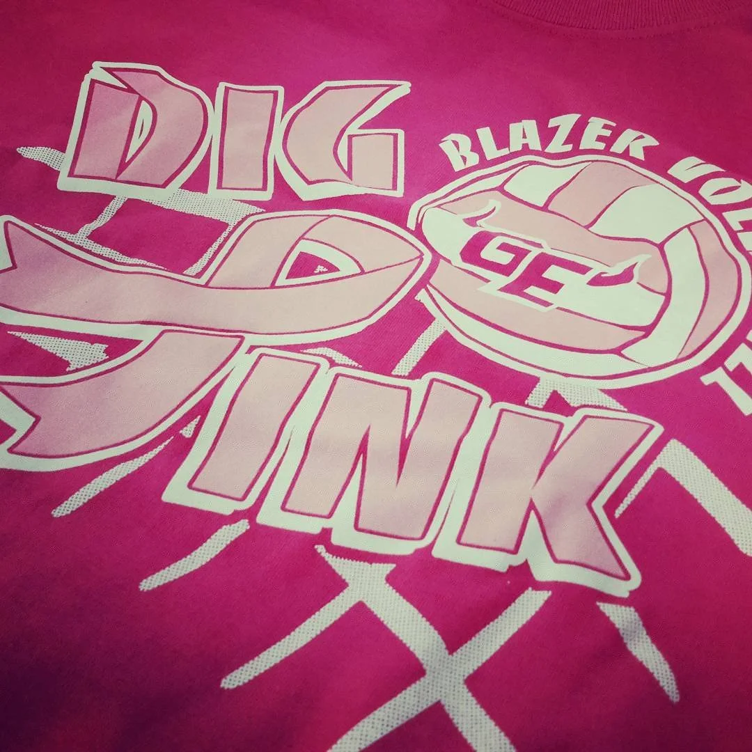 Pink athletic shirt with basketball graphics and lettering.