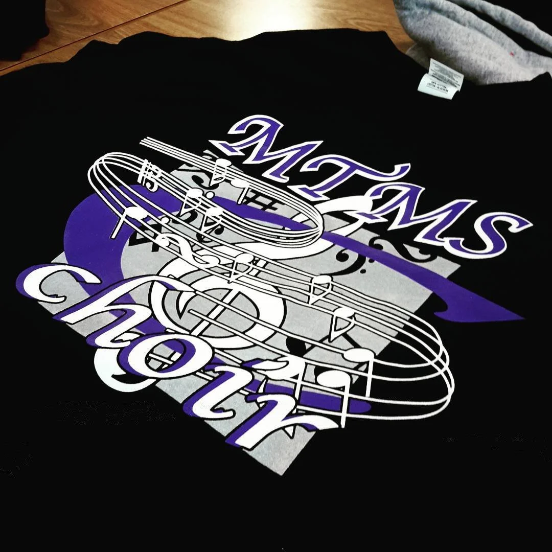 Black T-shirt with purple and white musical graphics.