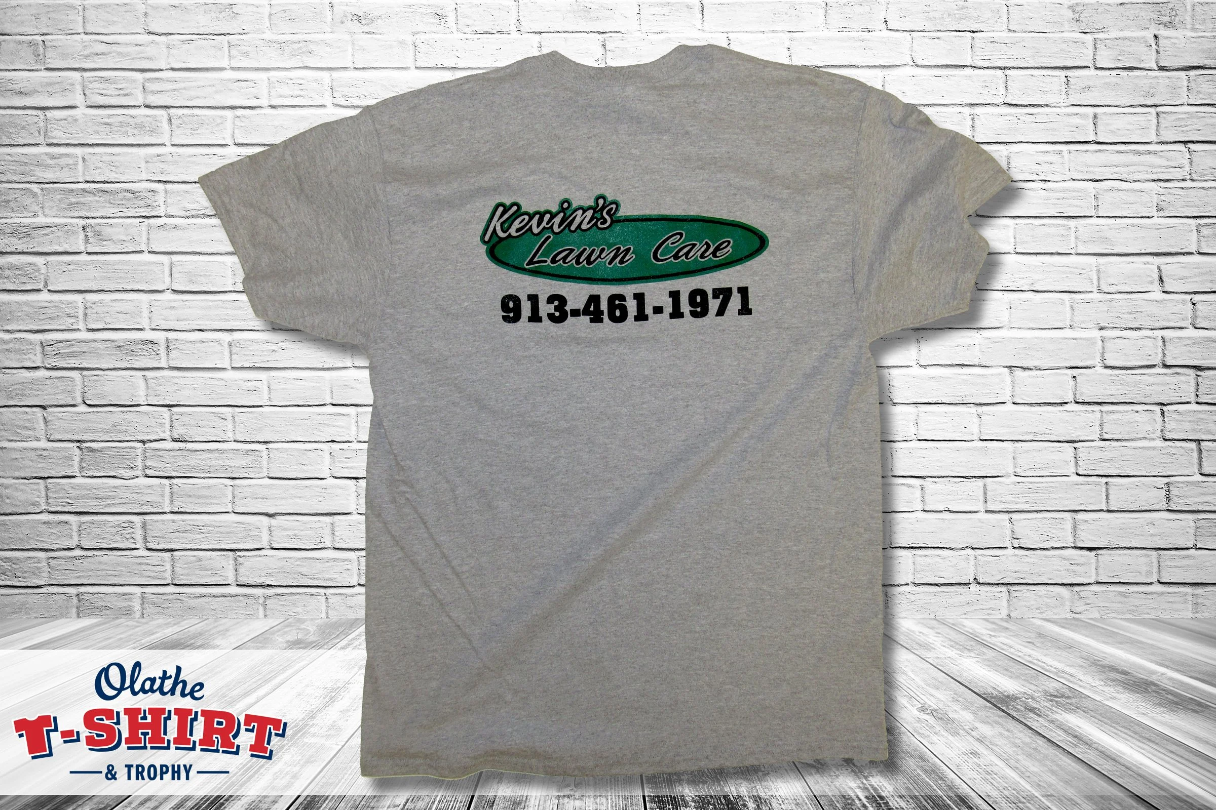 Gray lawn-care company shirt with printed business information.