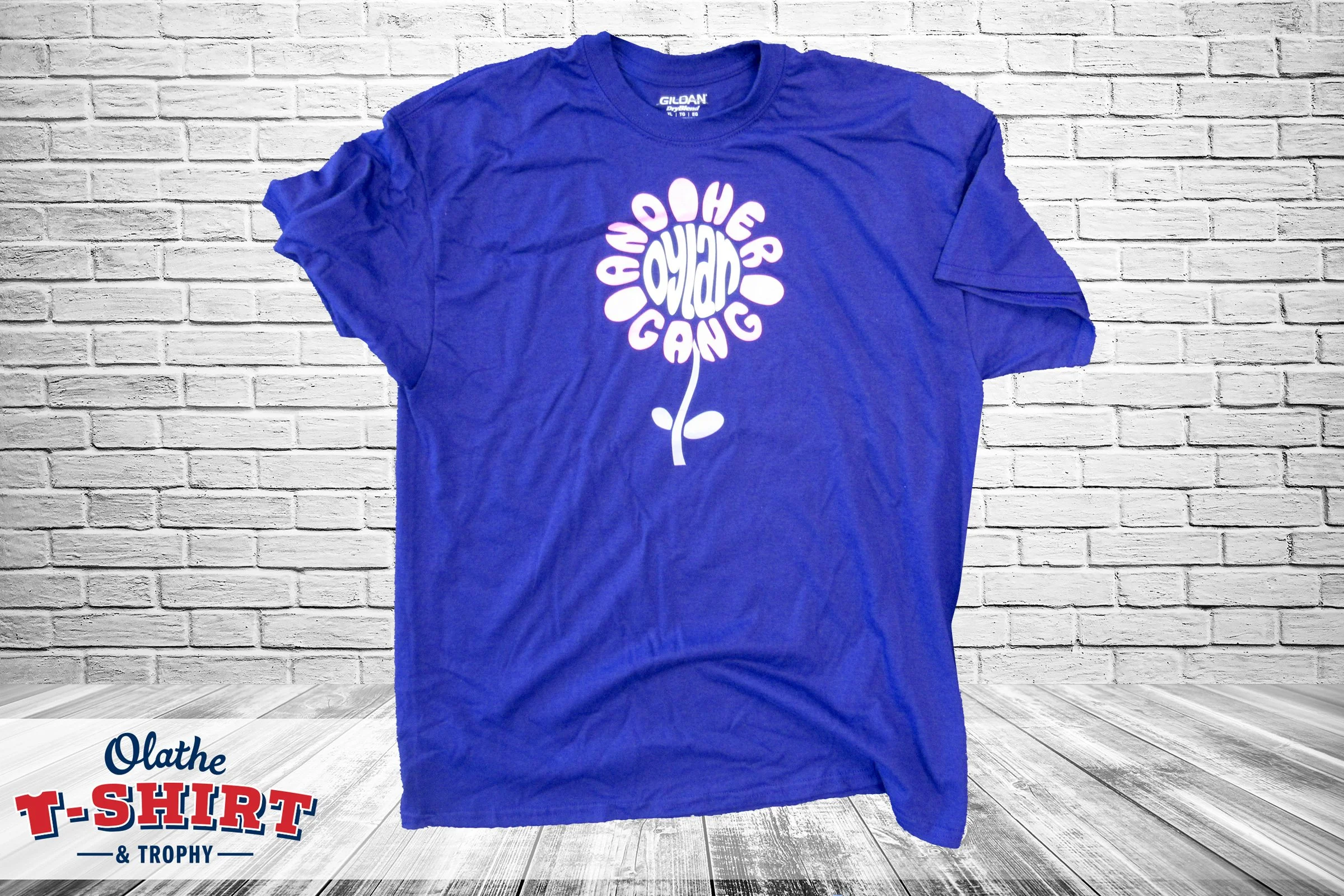 Blue shirt with an apple-shaped design made from white lettering.