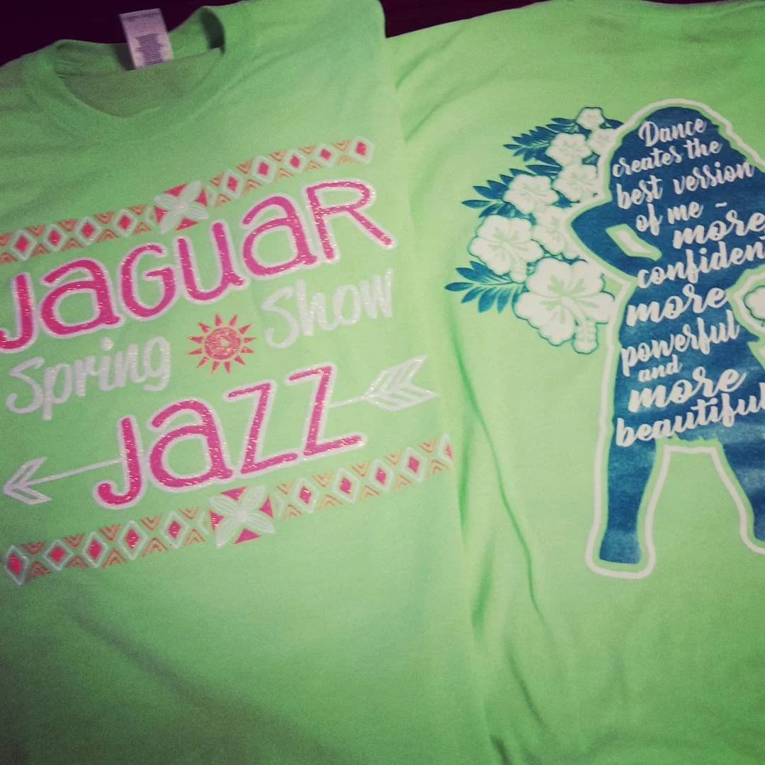 Light green apparel with pink and white lettering and decorative graphics.