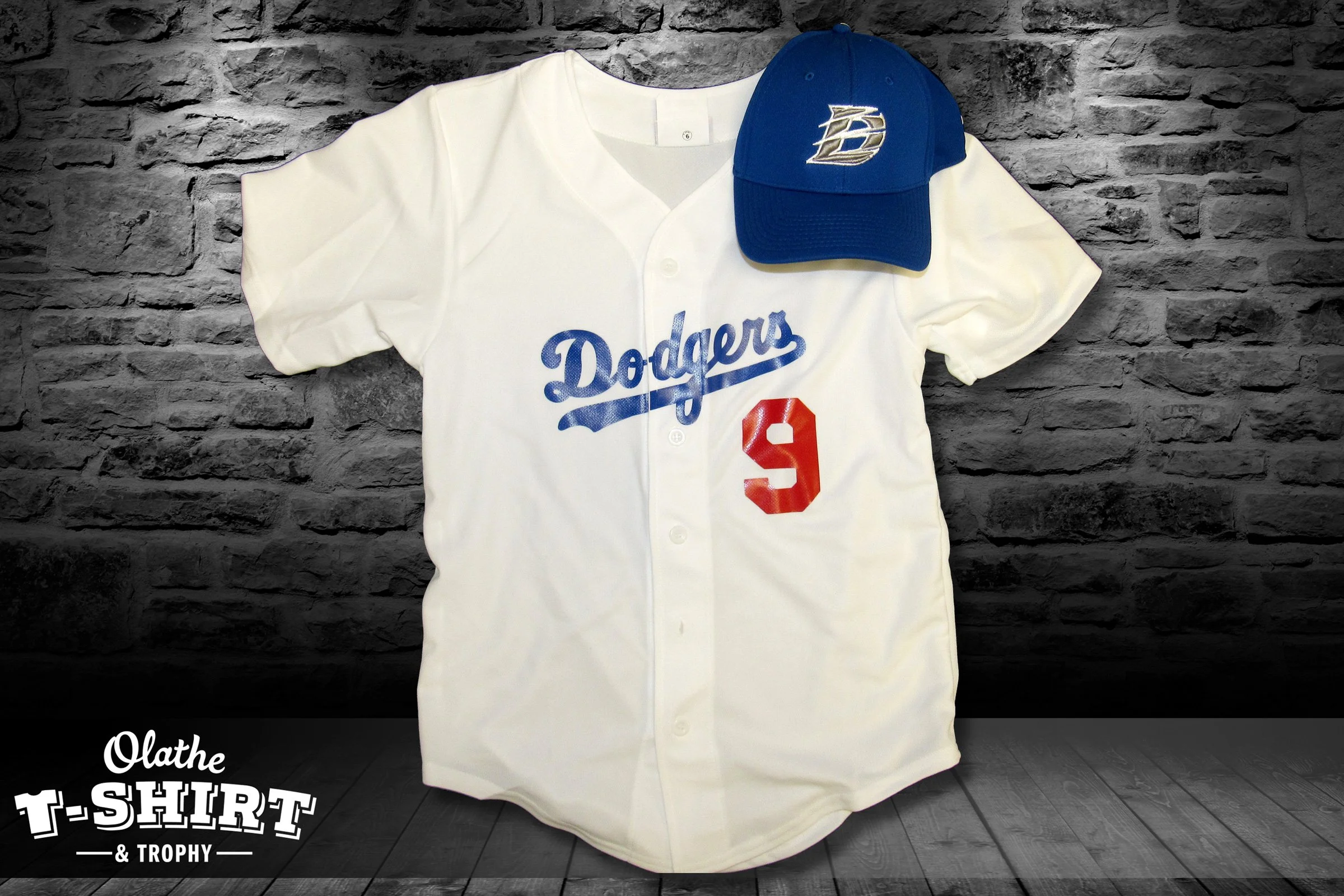 Baseball jersey and coordinating blue cap displayed against a brick wall.