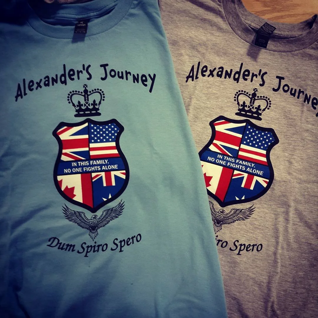 Two shirts with a heraldic shield, crown, flags and family-support lettering.