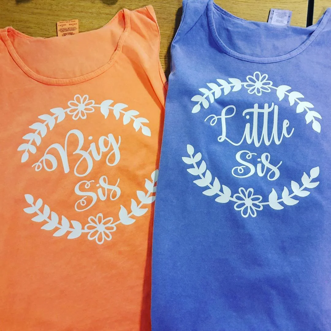 Green and pink sleeveless shirts with a pineapple wearing sunglasses and swim-team lettering.