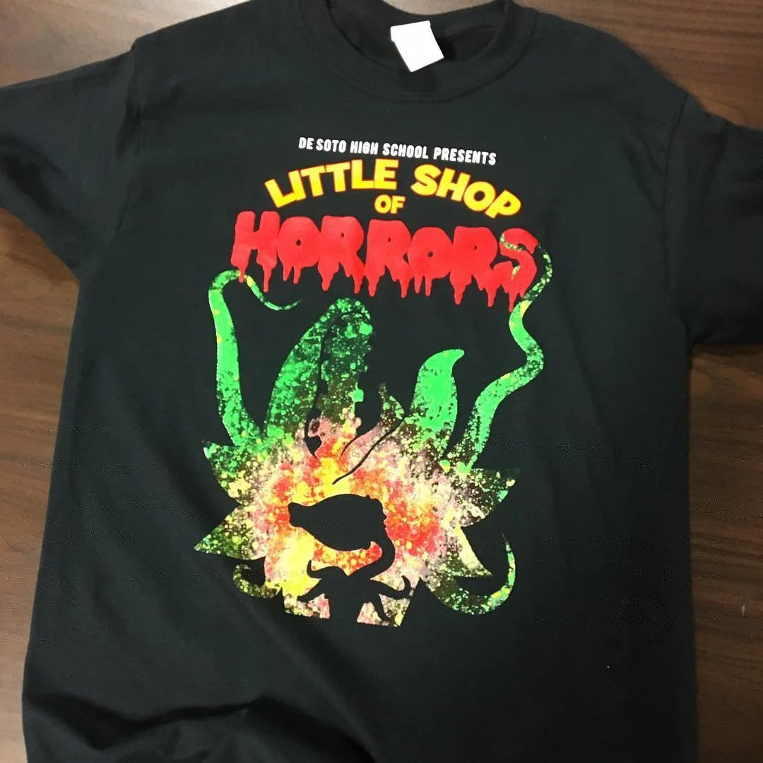 Black De Soto High School Little Shop of Horrors shirt with a colorful theatrical illustration.