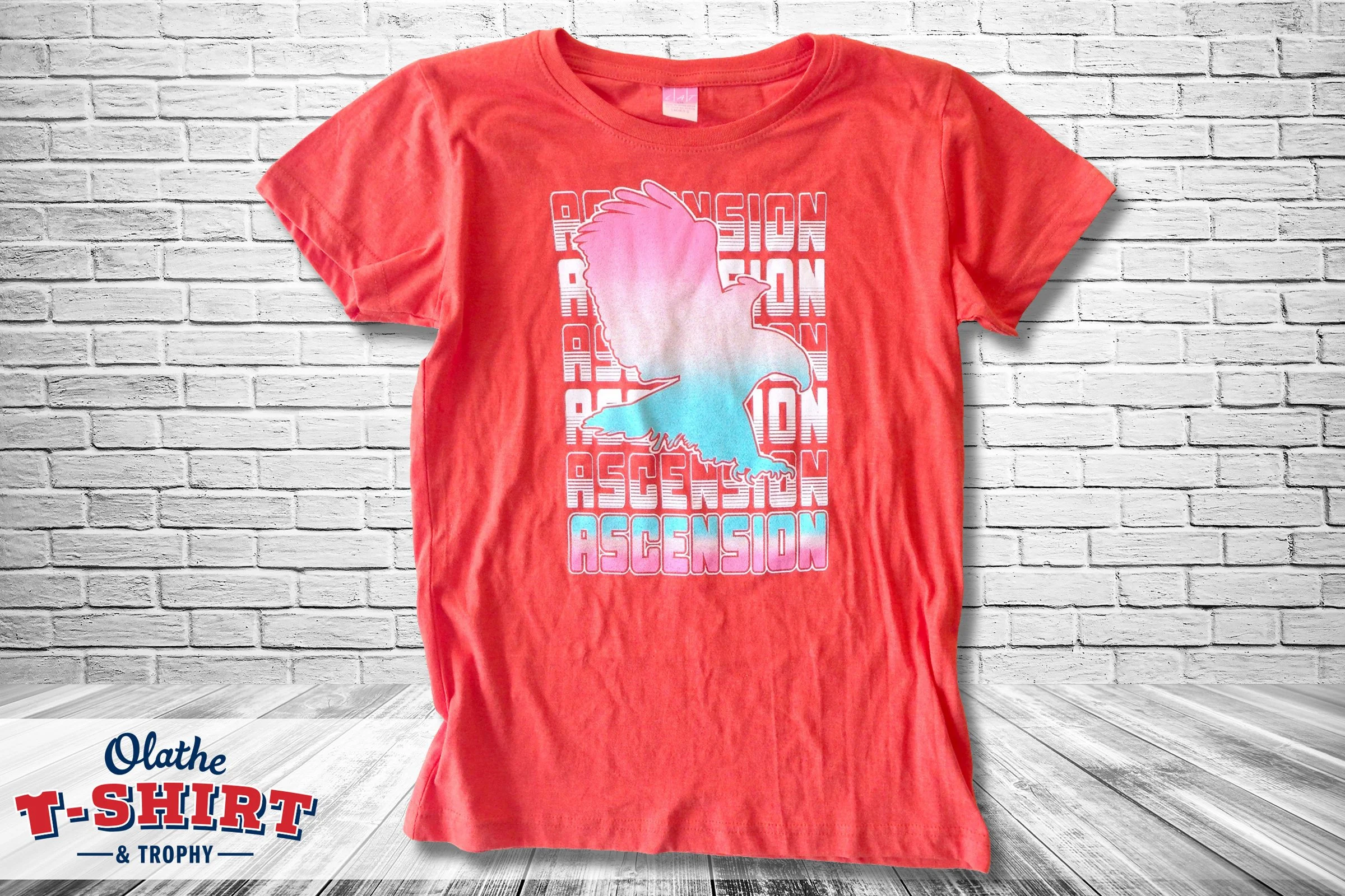Red shirt with a pink and blue bird graphic and repeated lettering.