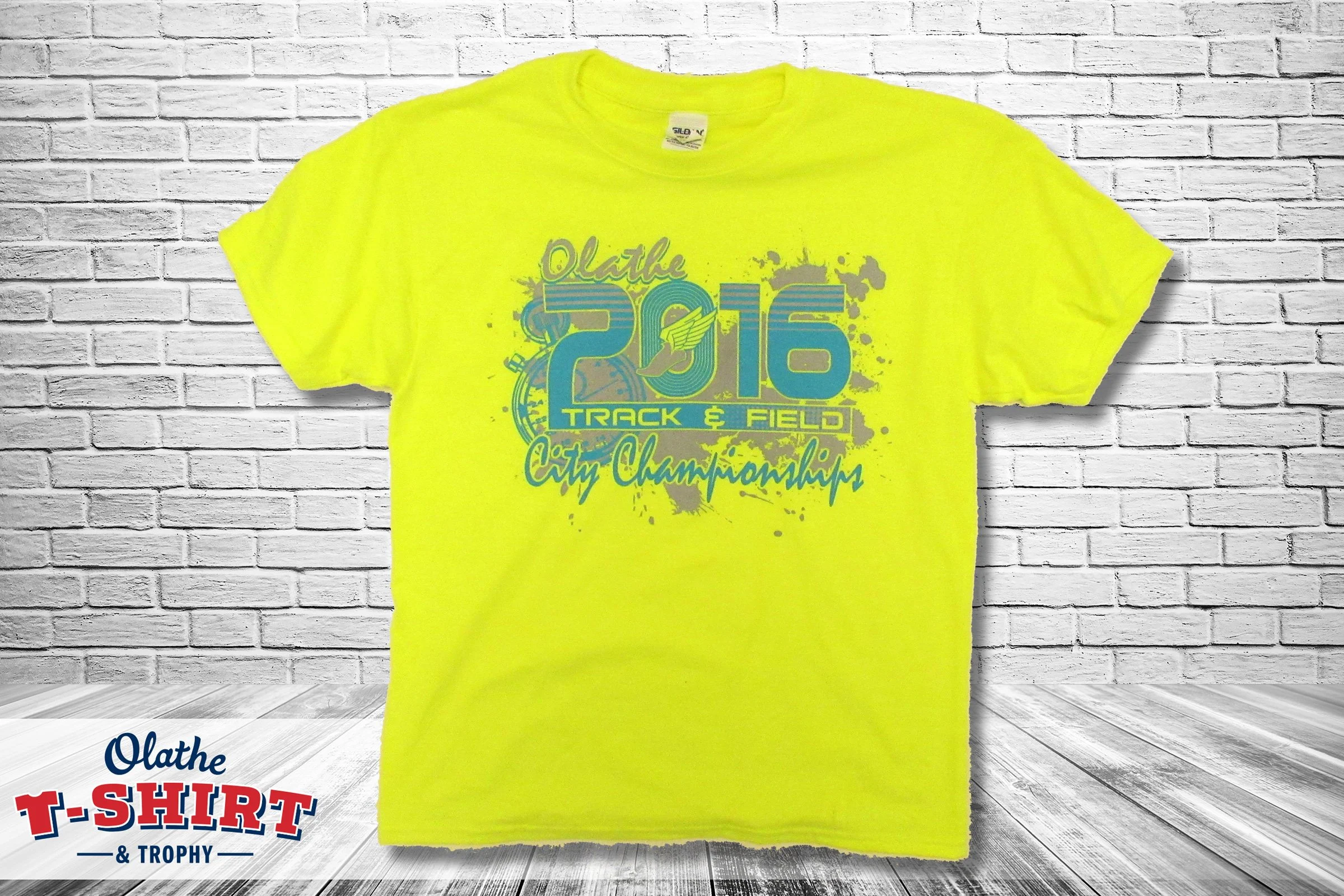 Bright yellow Olathe City Championships T-shirt with sports graphics.