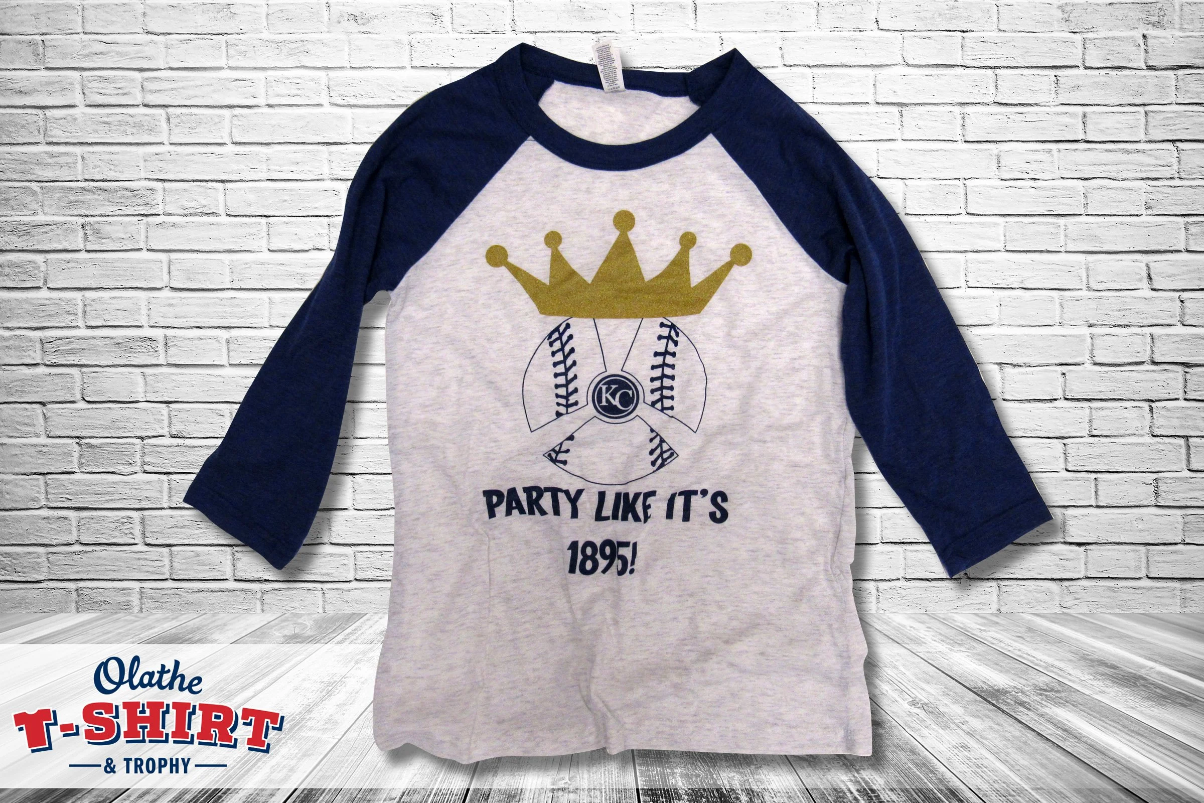 White and blue baseball-style shirt with a crown, baseball and Kansas City graphic.